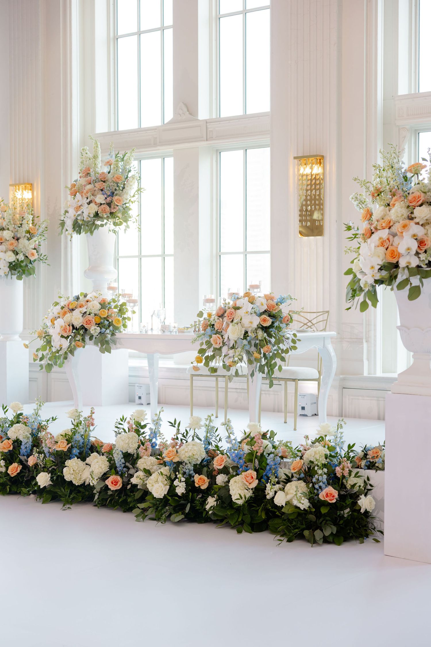 Elegant wedding space with cascading floral installations and natural light streaming through tall windows.