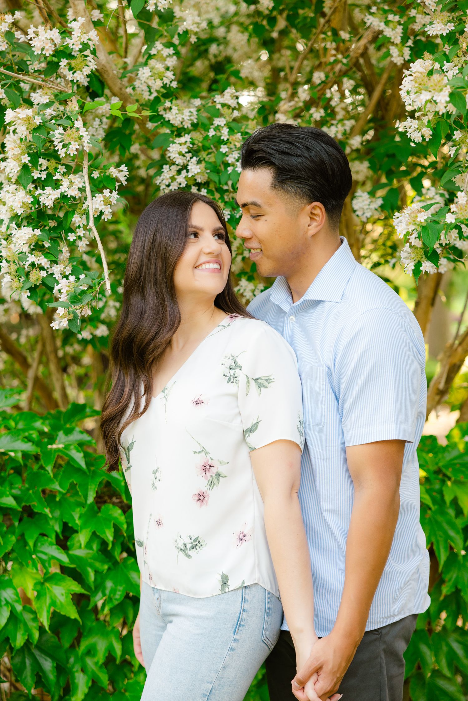 Sweet outdoor portrait of a couple sharing intimate moment among flowering spring trees.