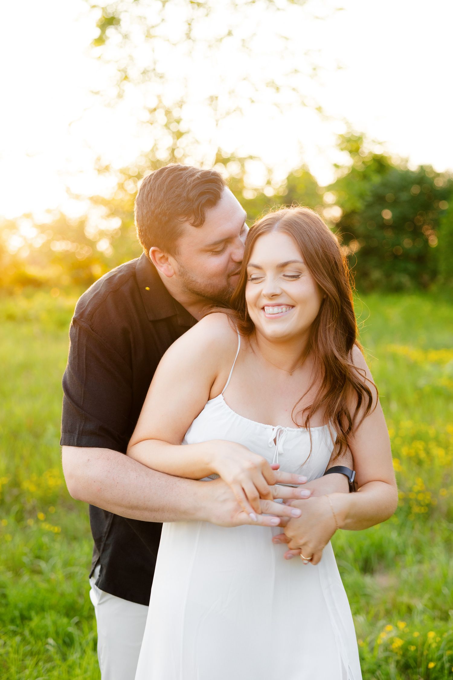 Tender moment between couple during sunset photoshoot in a flowering meadow.