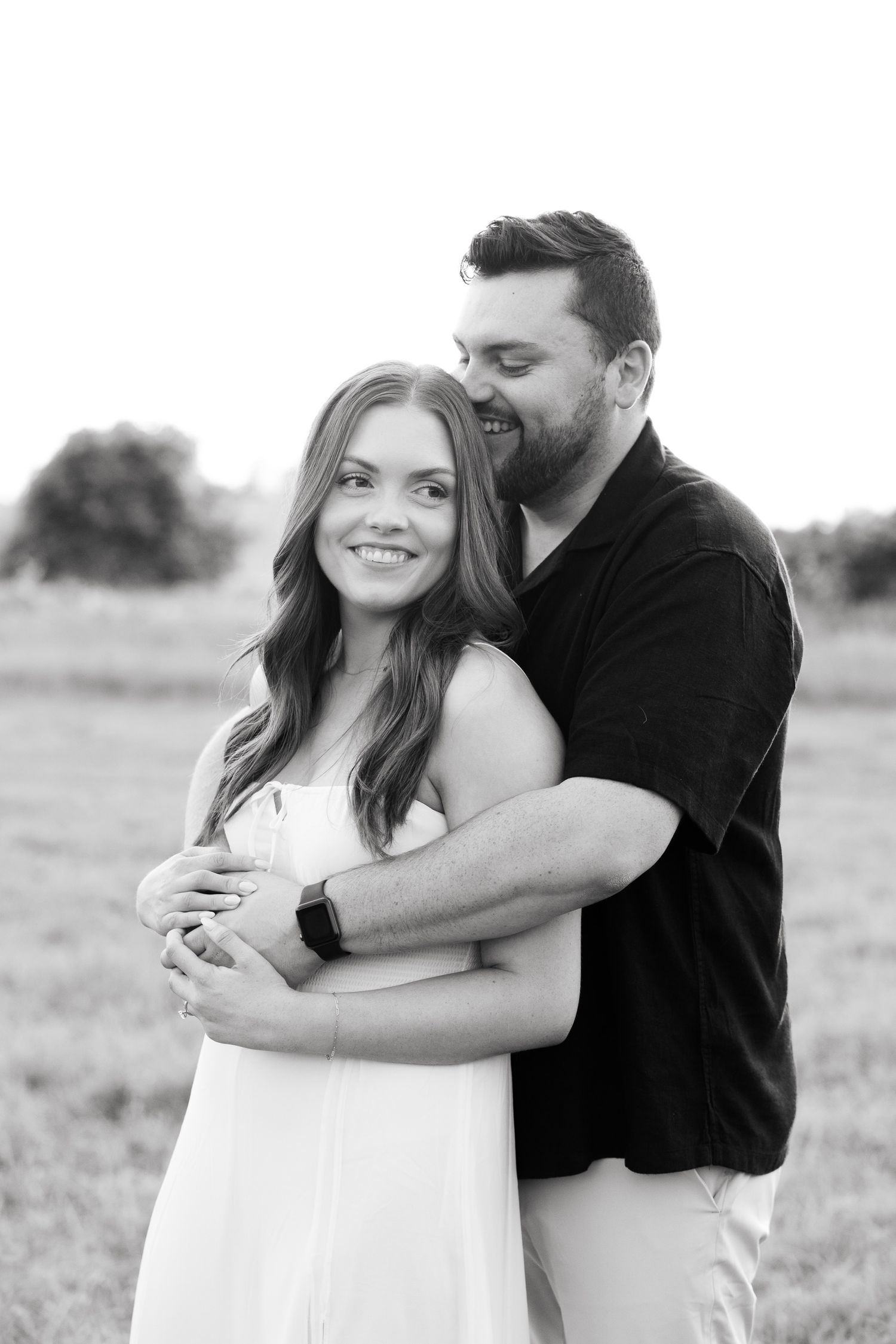 Black and white candid shot of couple laughing while embracing outdoors.