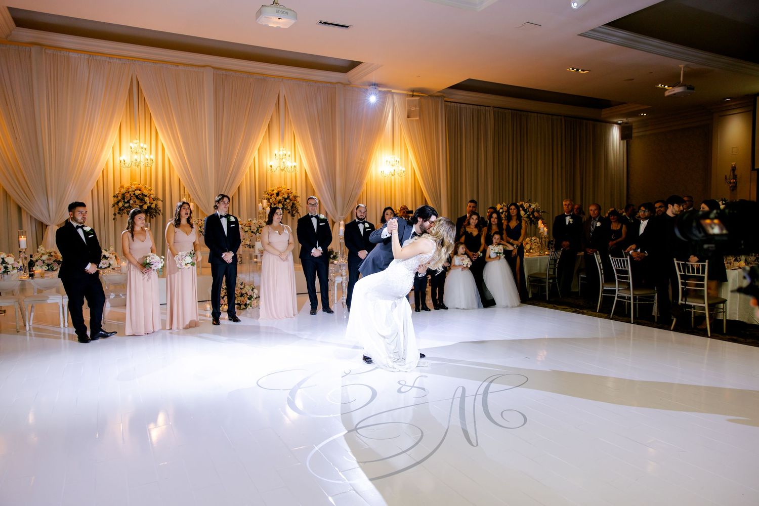 Couple performs first dance on elegant monogrammed white dance floor.