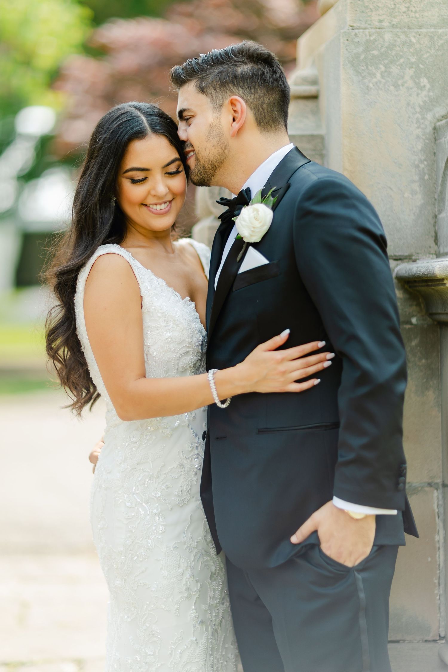 Romantic wedding portrait of couple in formal attire sharing an intimate moment outdoors.