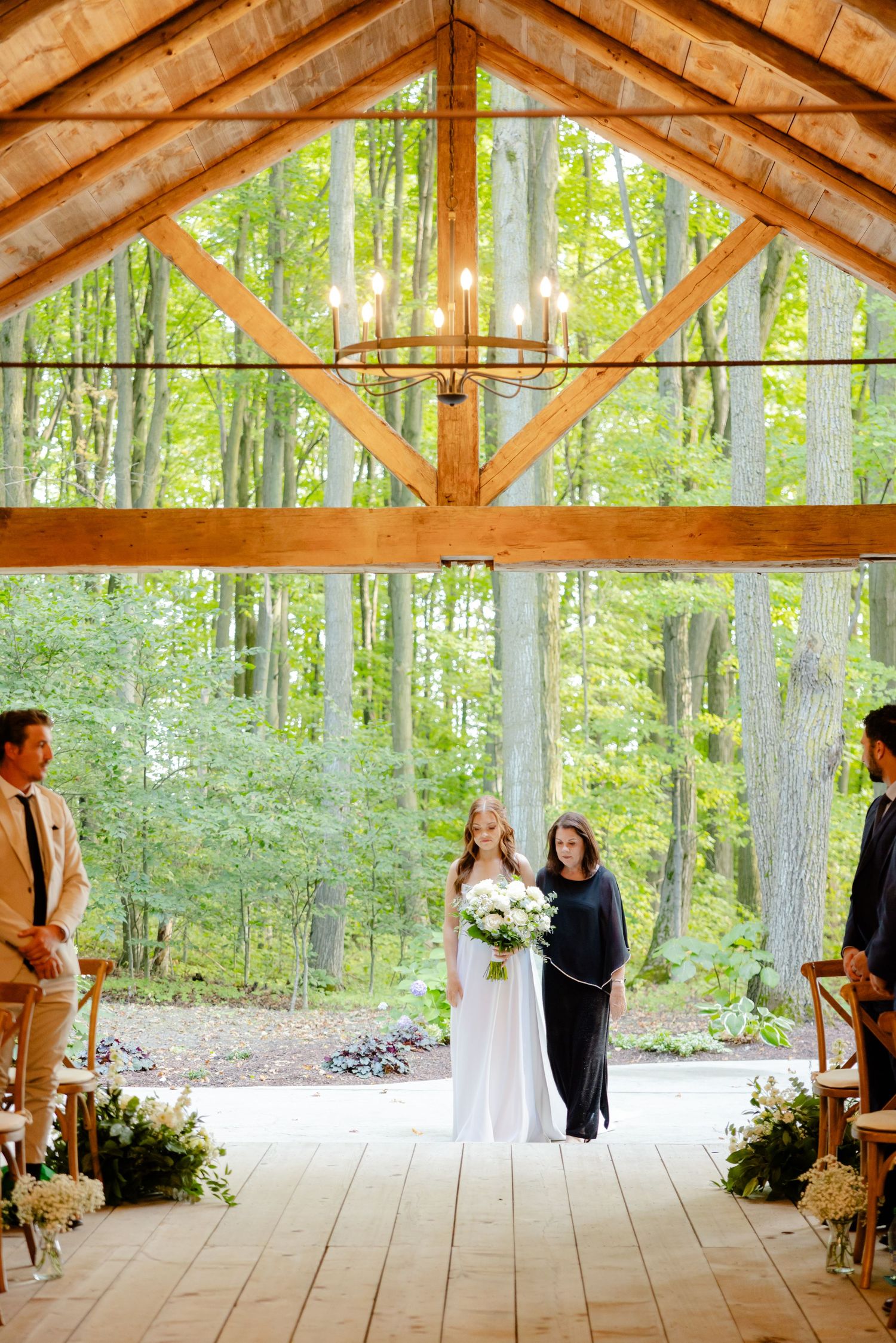 Wedding ceremony in progress inside a wooden pavilion surrounded by lush forest greenery.