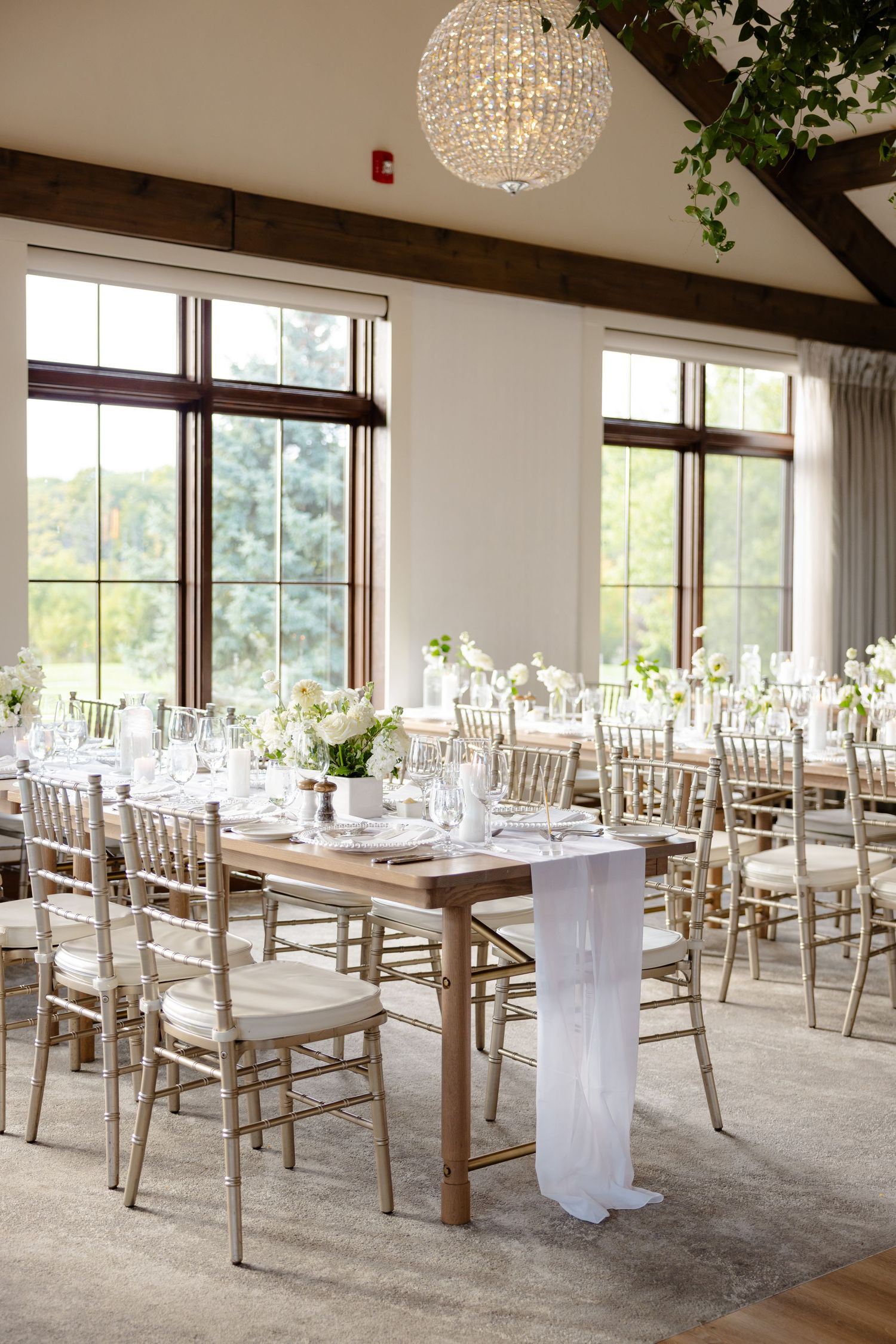 Rustic-elegant reception space with crystal chandelier and natural light from large windows.