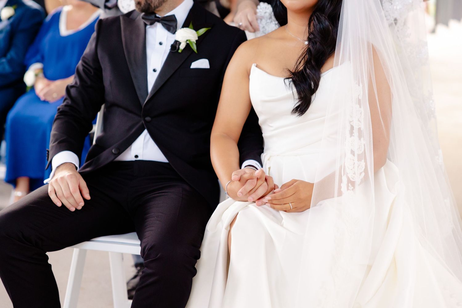 Couple seated during their wedding ceremony in formal black tie attire.