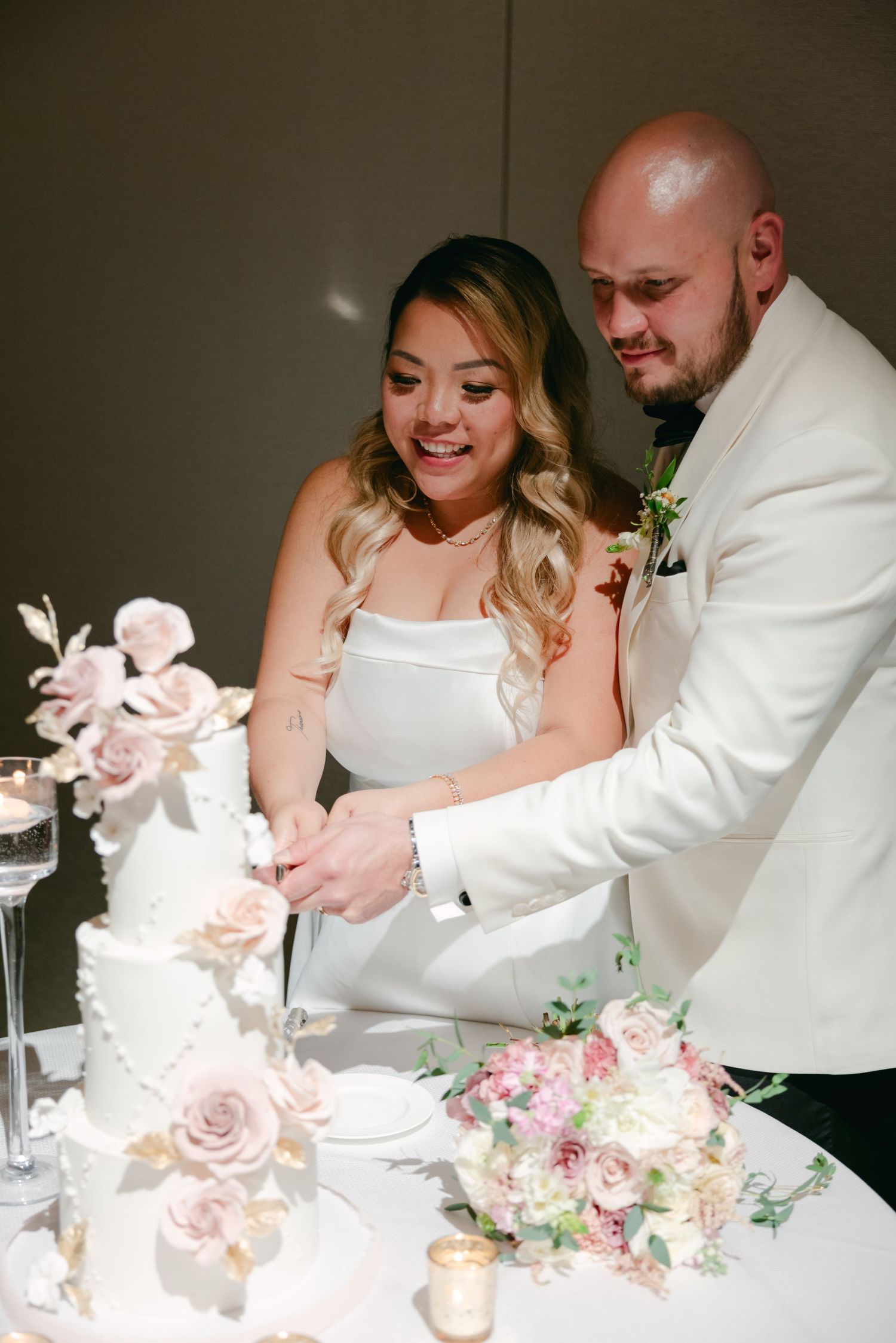 Happy couple shares a moment while cutting their floral-decorated wedding cake.