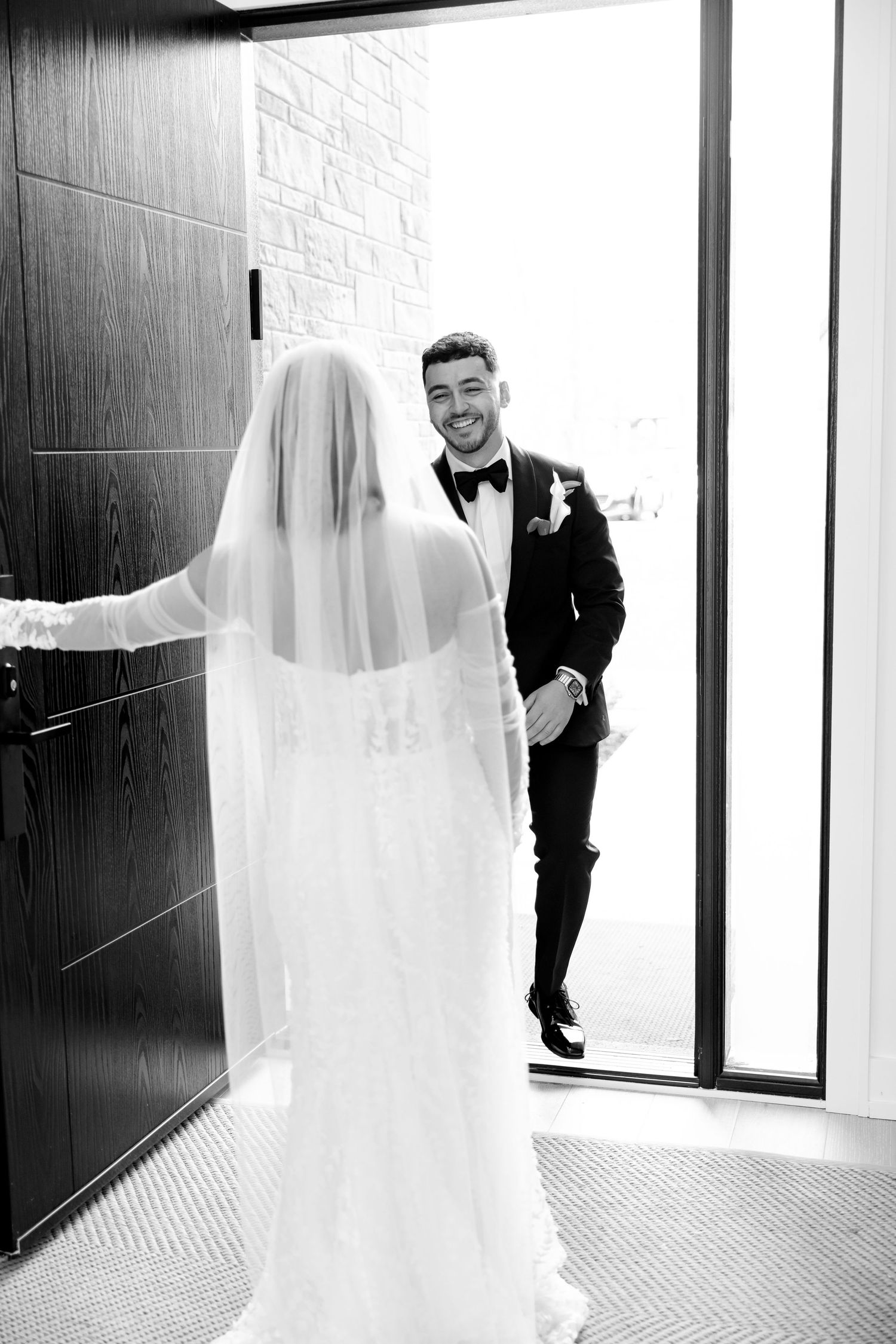First look wedding moment showing emotional reaction through doorway.