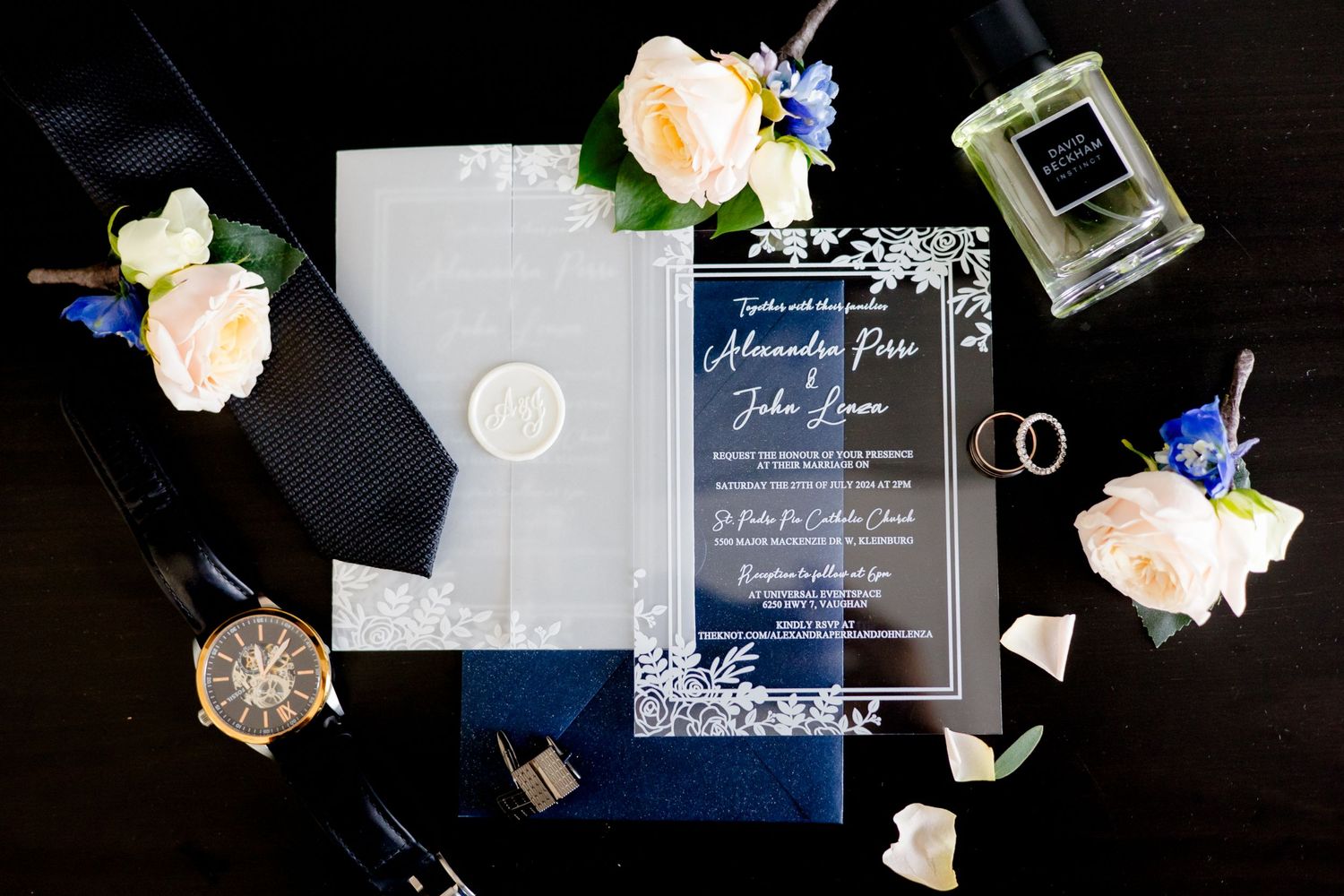 Wedding invitation suite in navy and white with floral accents and perfume bottle.