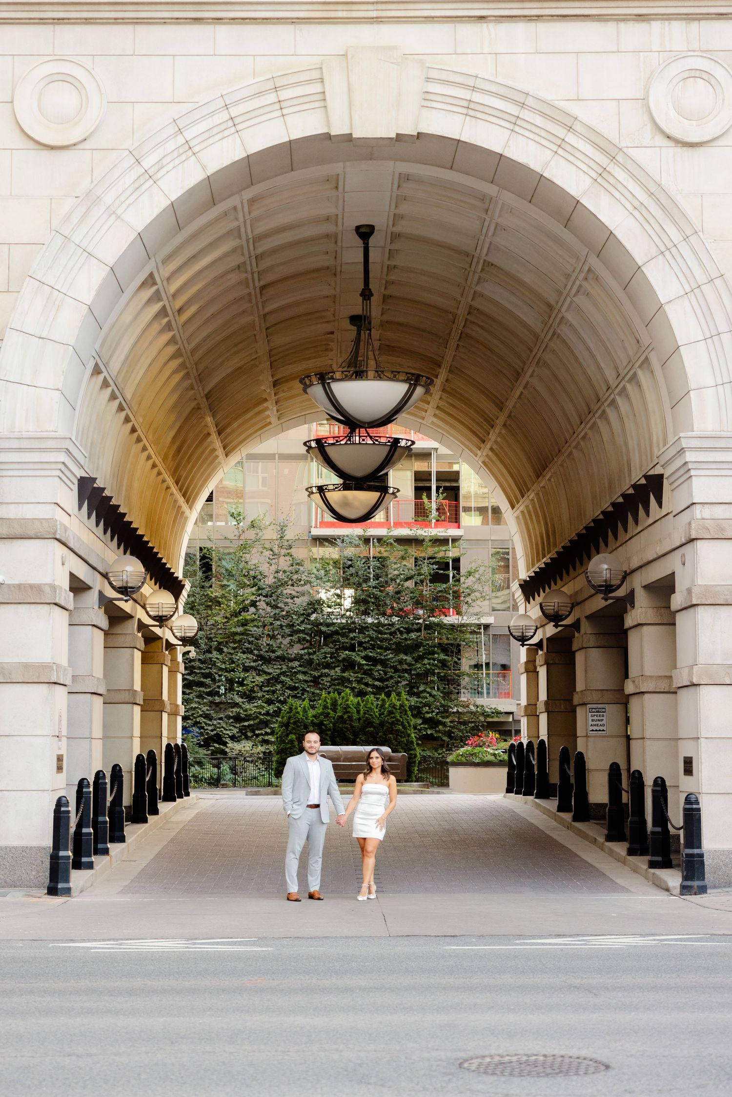 Couple walks through grand archway with elegant architectural details.