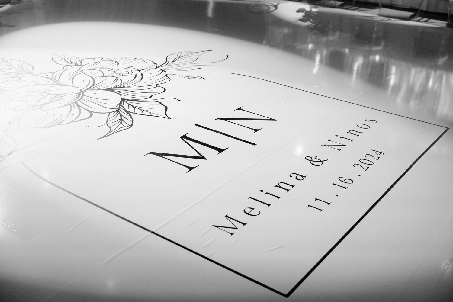 Black and white close-up of an elegant wedding menu card with floral design.