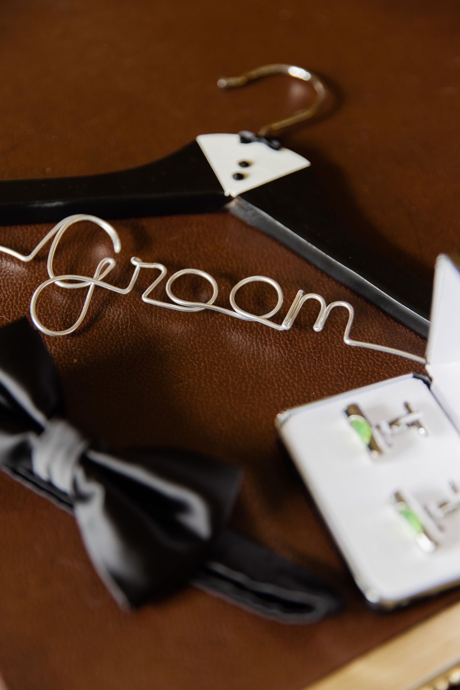 Custom wire hanger spelling out 'groom' with a black bow tie and cufflinks.