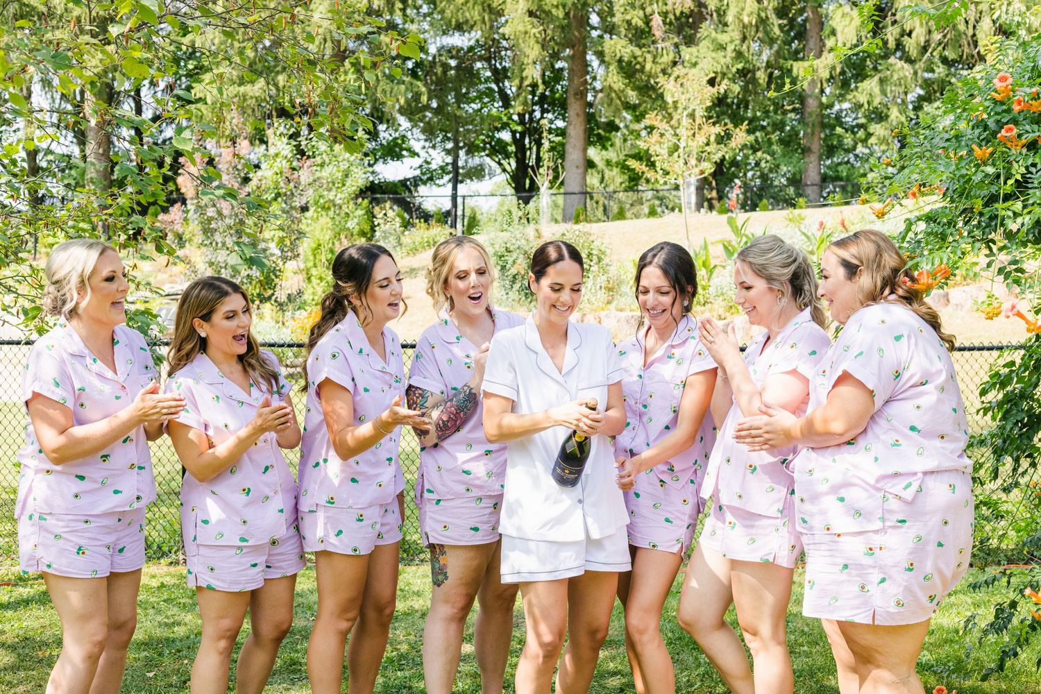 Bridesmaids in matching floral robes laughing together outdoors.
