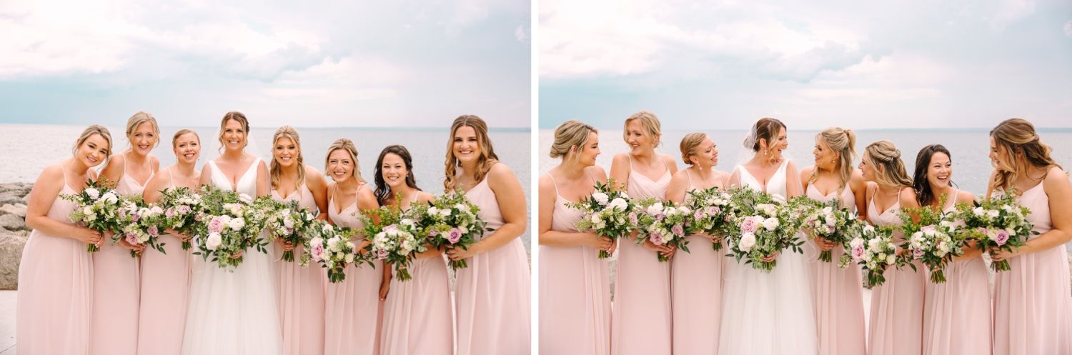 Wedding party in blush pink dresses pose together by the water for formal photos.