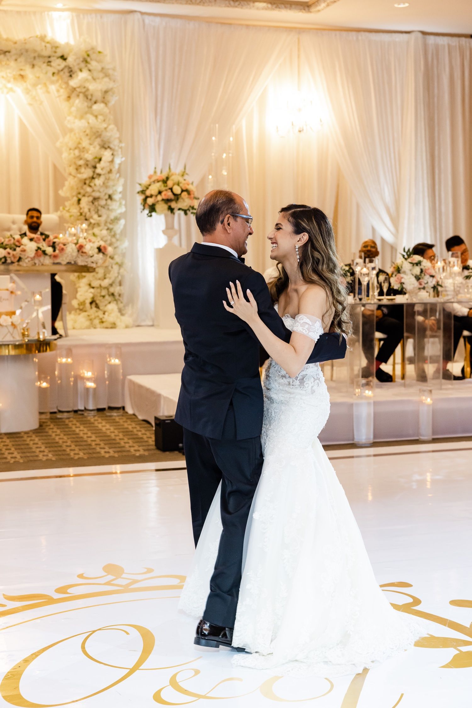 Couple shares romantic dance moment on monogrammed dance floor at elegant wedding reception.