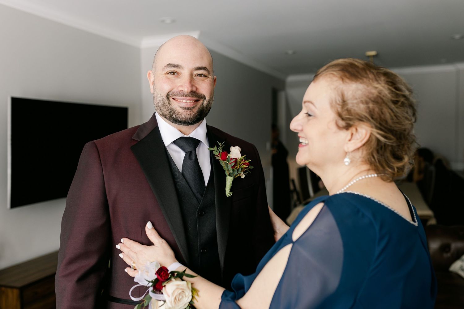 A joyful moment shared between two people in formal attire, with burgundy and navy blue clothing.
