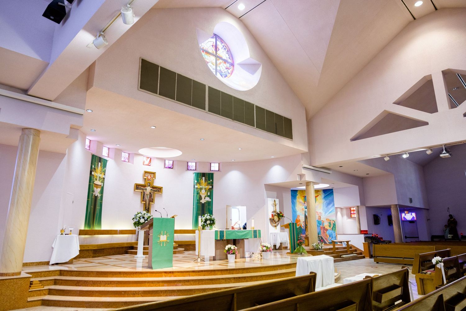 Interior view of a modern church sanctuary with vaulted ceiling and wooden pews arranged towards an altar area.