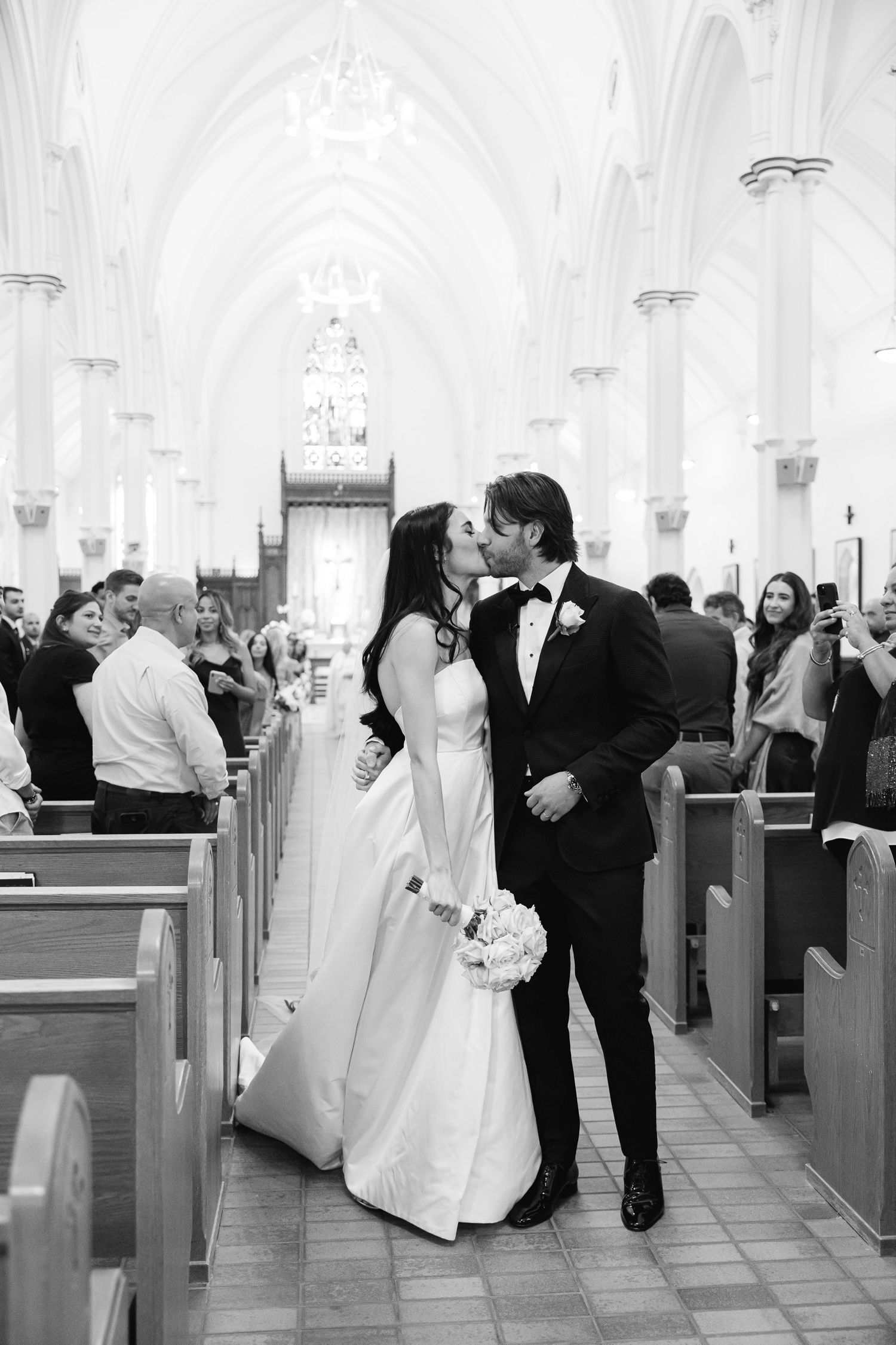 A romantic moment shared between newlyweds in a church aisle after their ceremony.