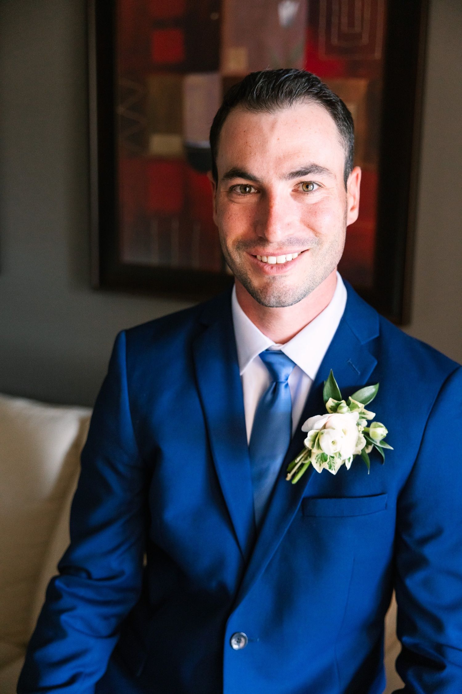 A formal portrait featuring a blue suit paired with a coordinating tie and white boutonnière.