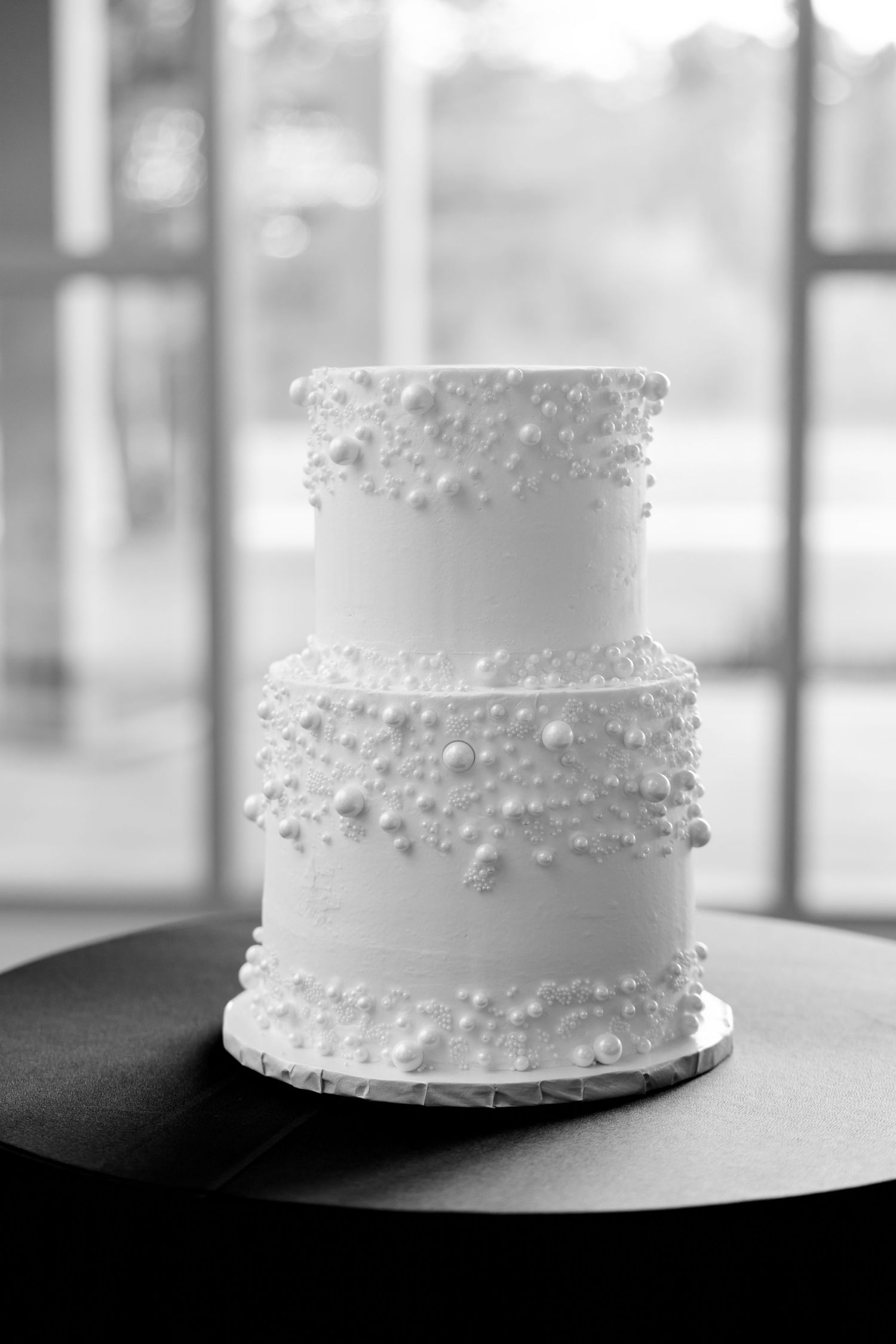 Classic white two-tier wedding cake with delicate pearl details.