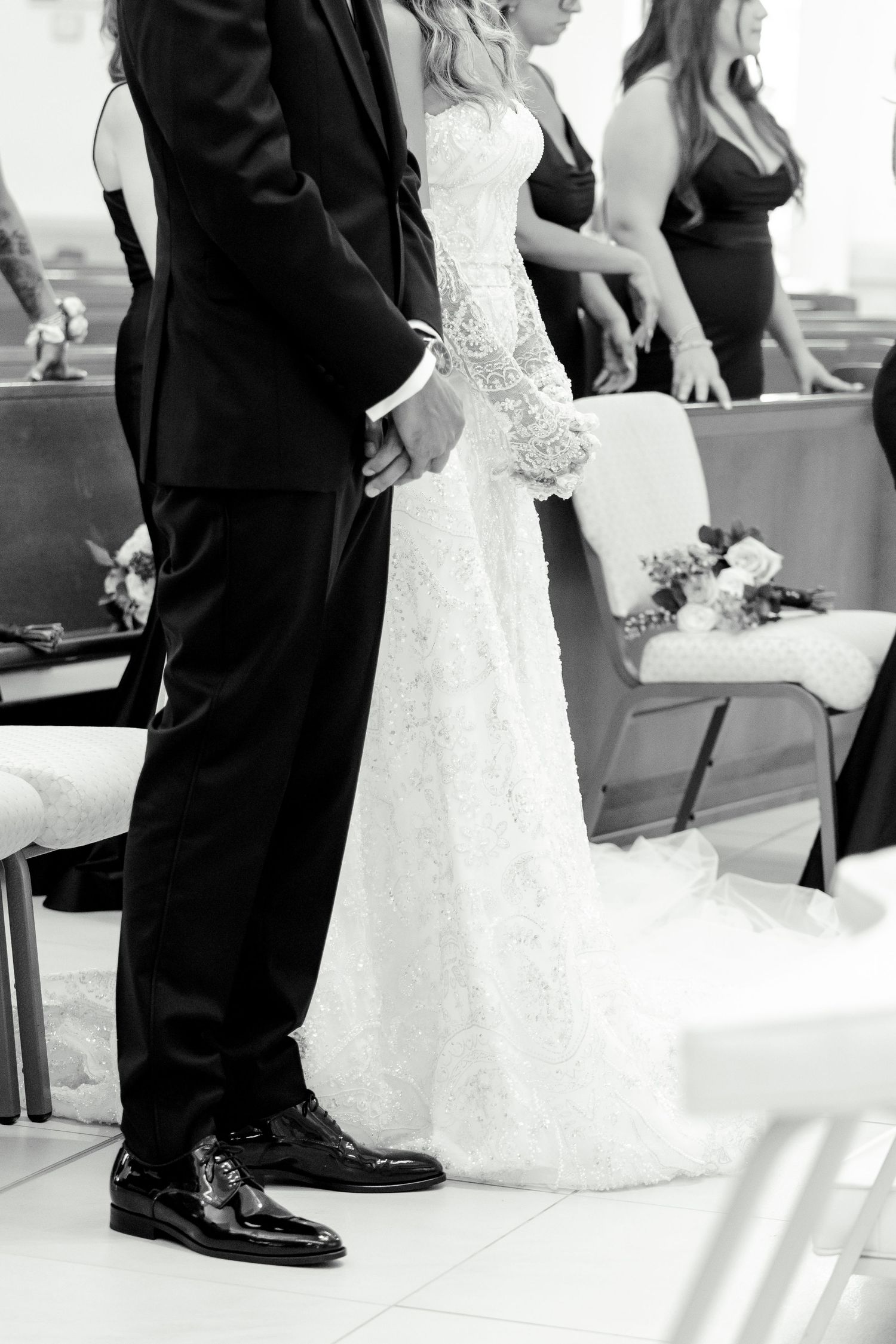 Black and white detail shot of formal wedding attire during the ceremony.