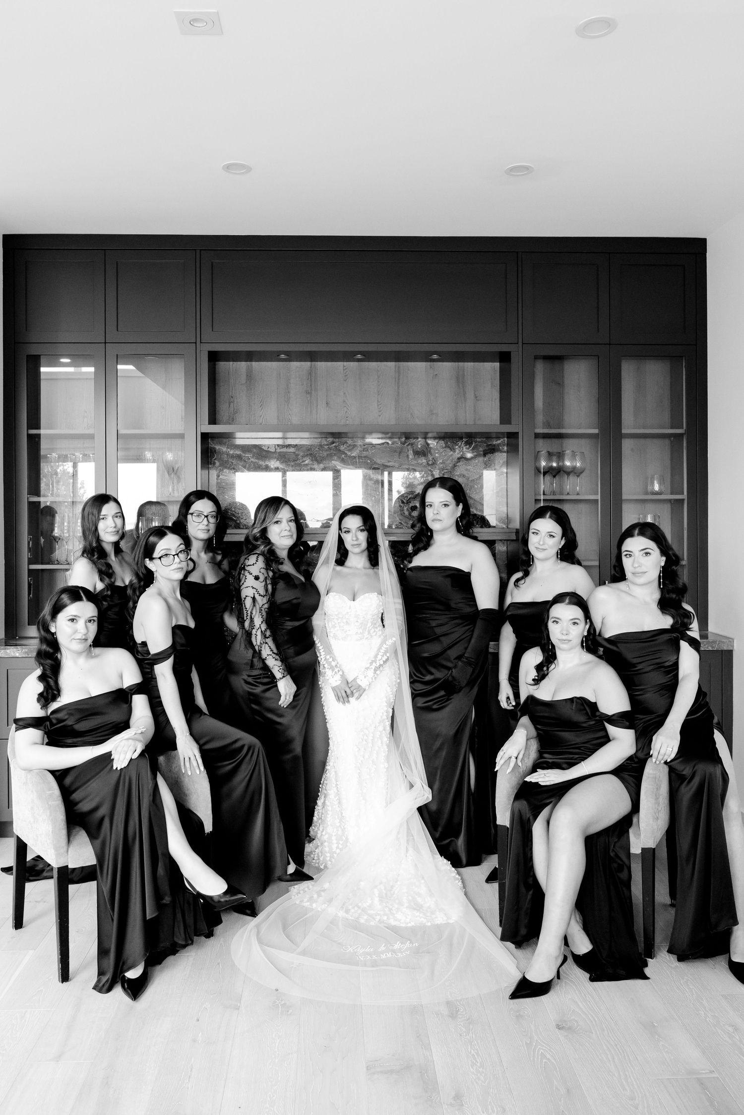 Black and white portrait of bridal party in elegant black dresses with bride in white.
