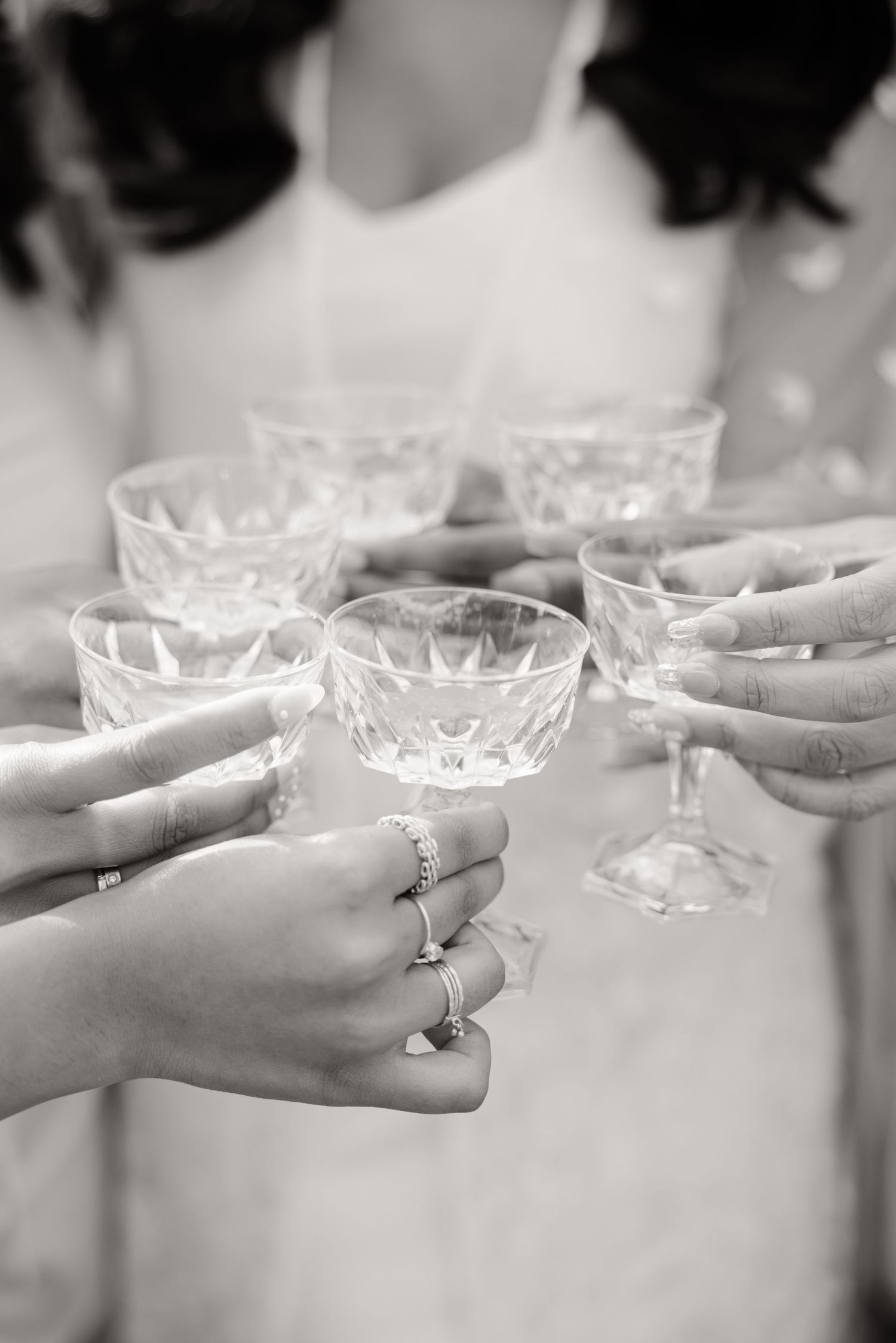 Black and white photo of crystal champagne glasses being raised in a toast.