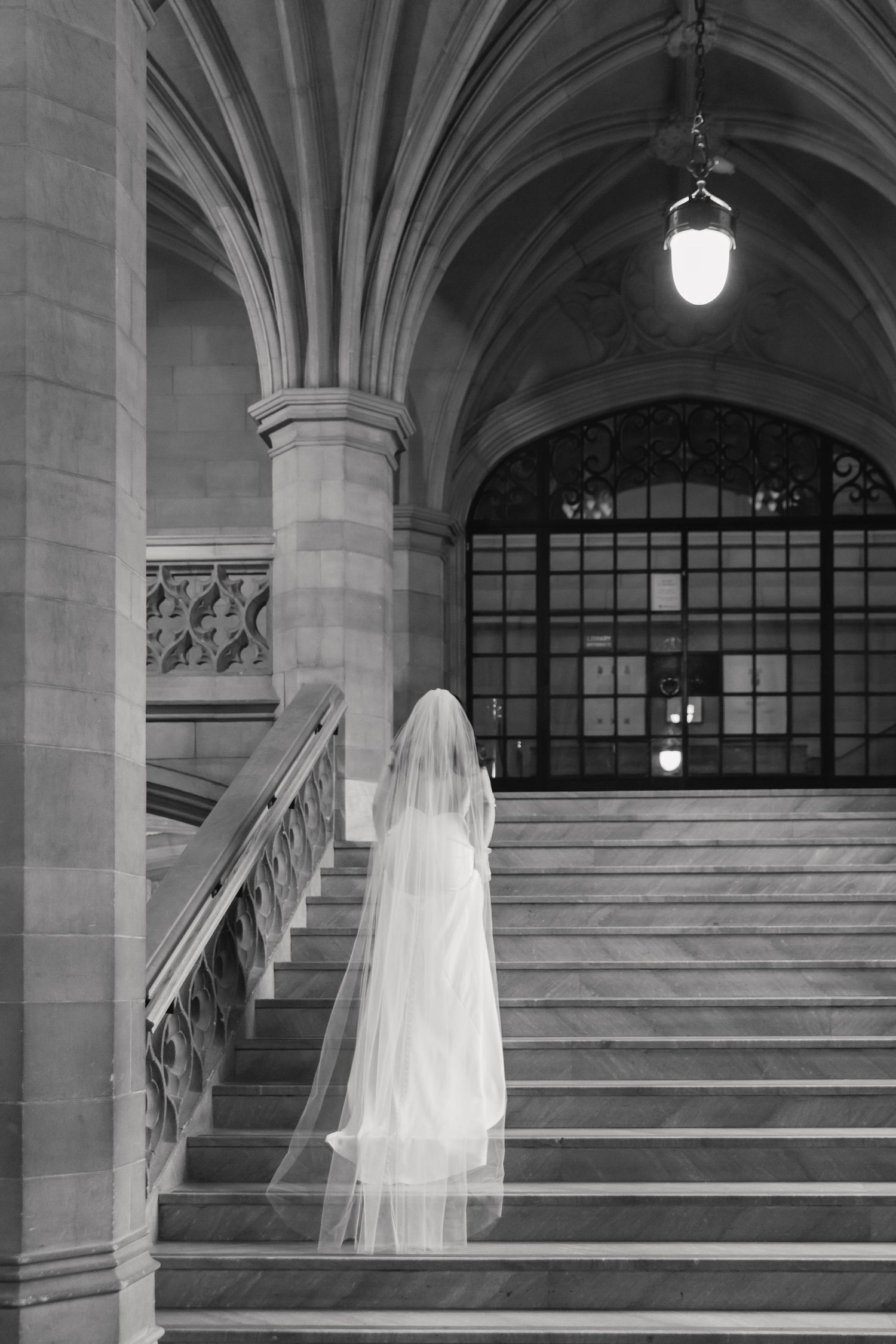Black and white photo of a wedding dress and veil silhouette on grand stone steps.