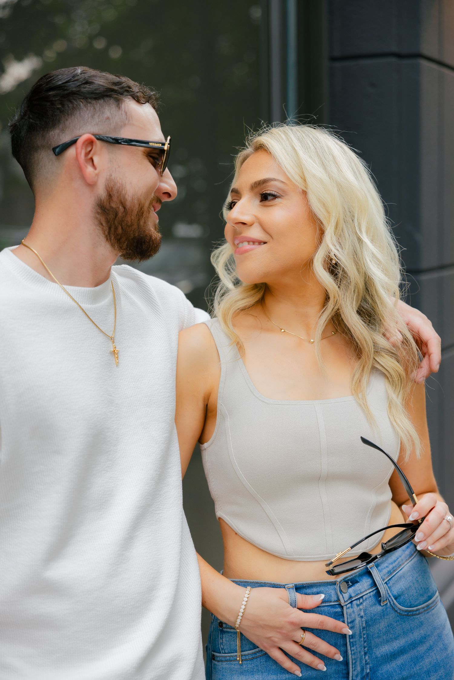 A couple in matching casual wear smiling at each other against a modern backdrop.