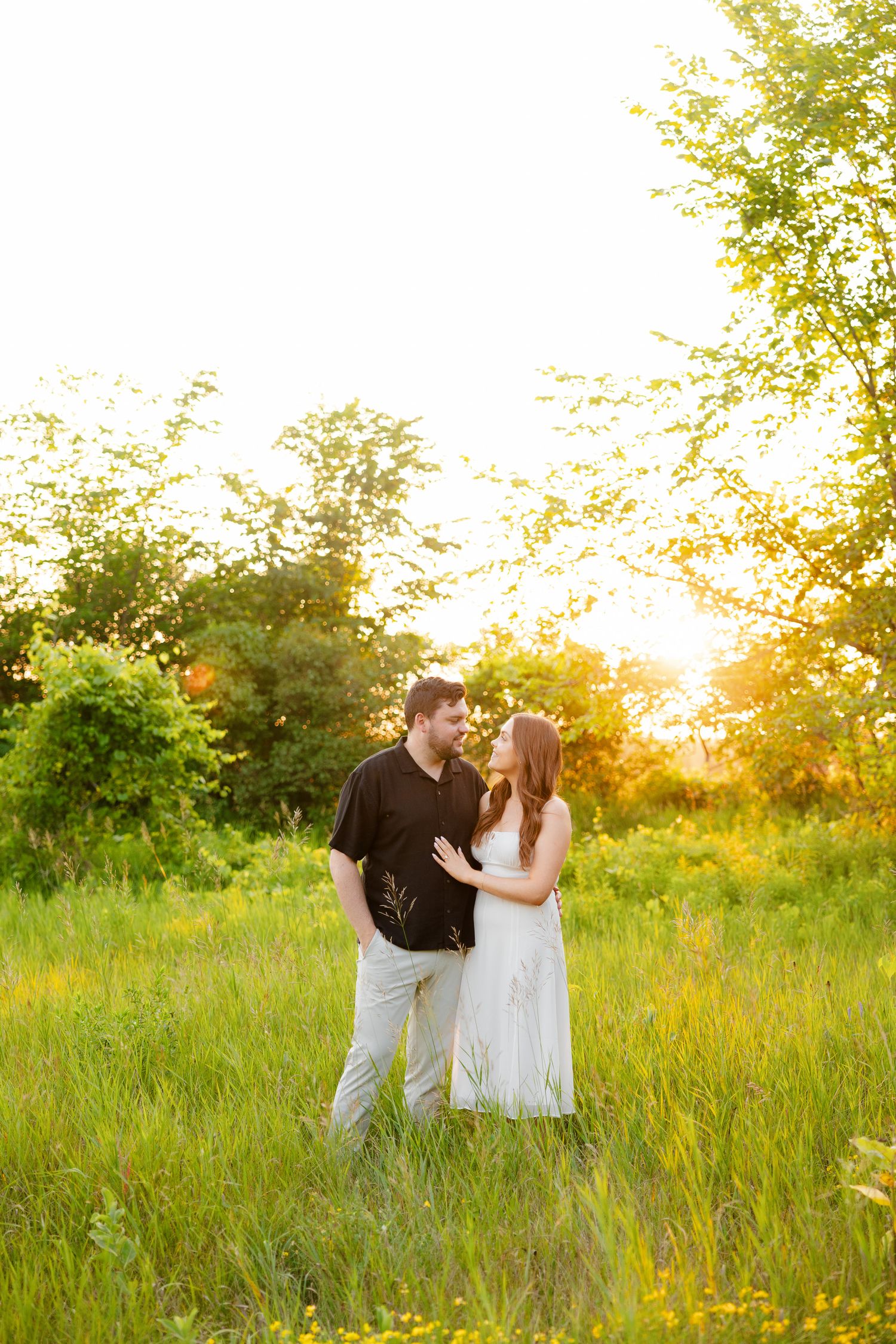 Loving couple shares romantic moment in sun-drenched field at golden hour.