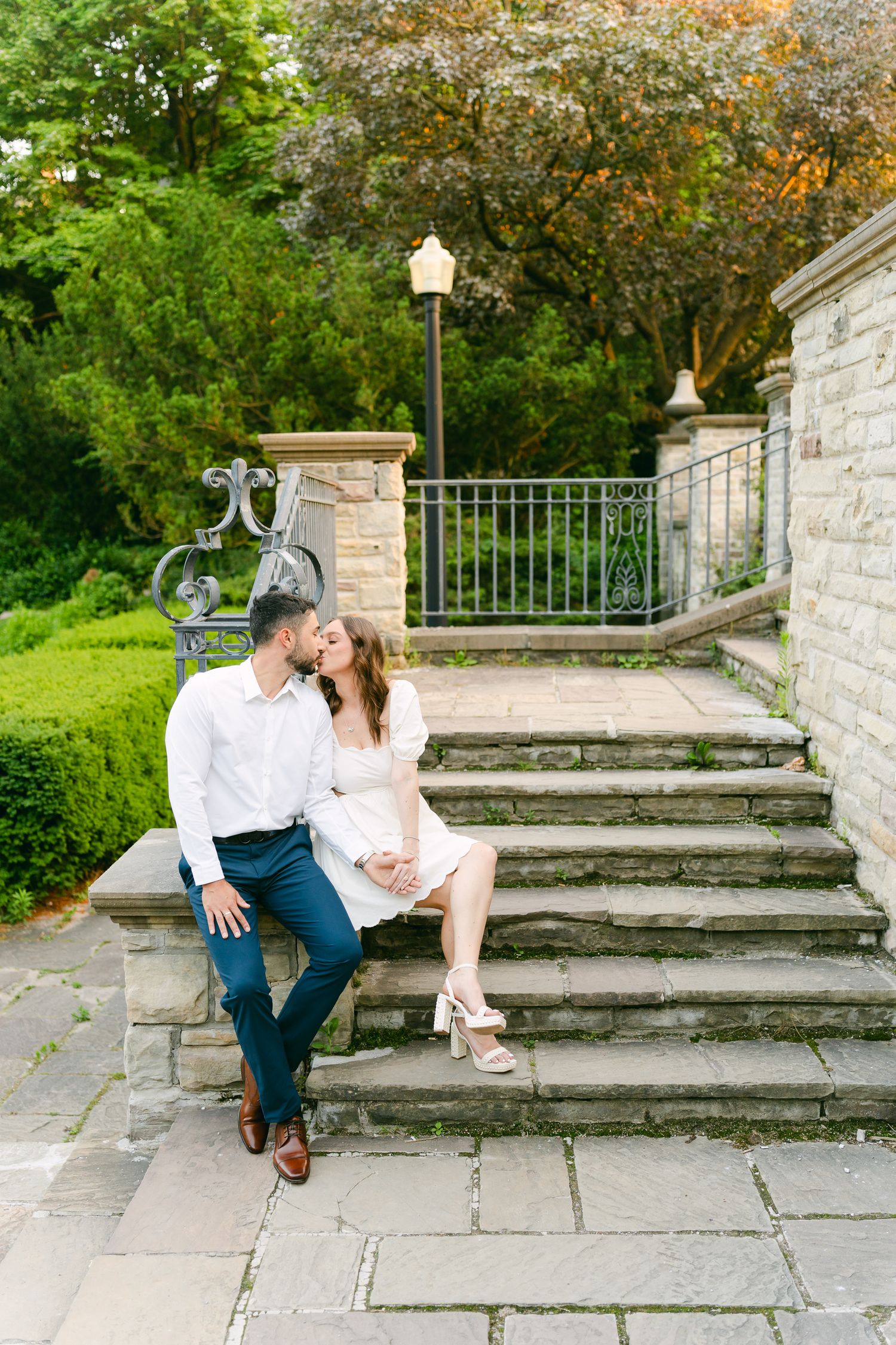 Romantic outdoor photo of two people sharing a tender moment on garden stone steps.