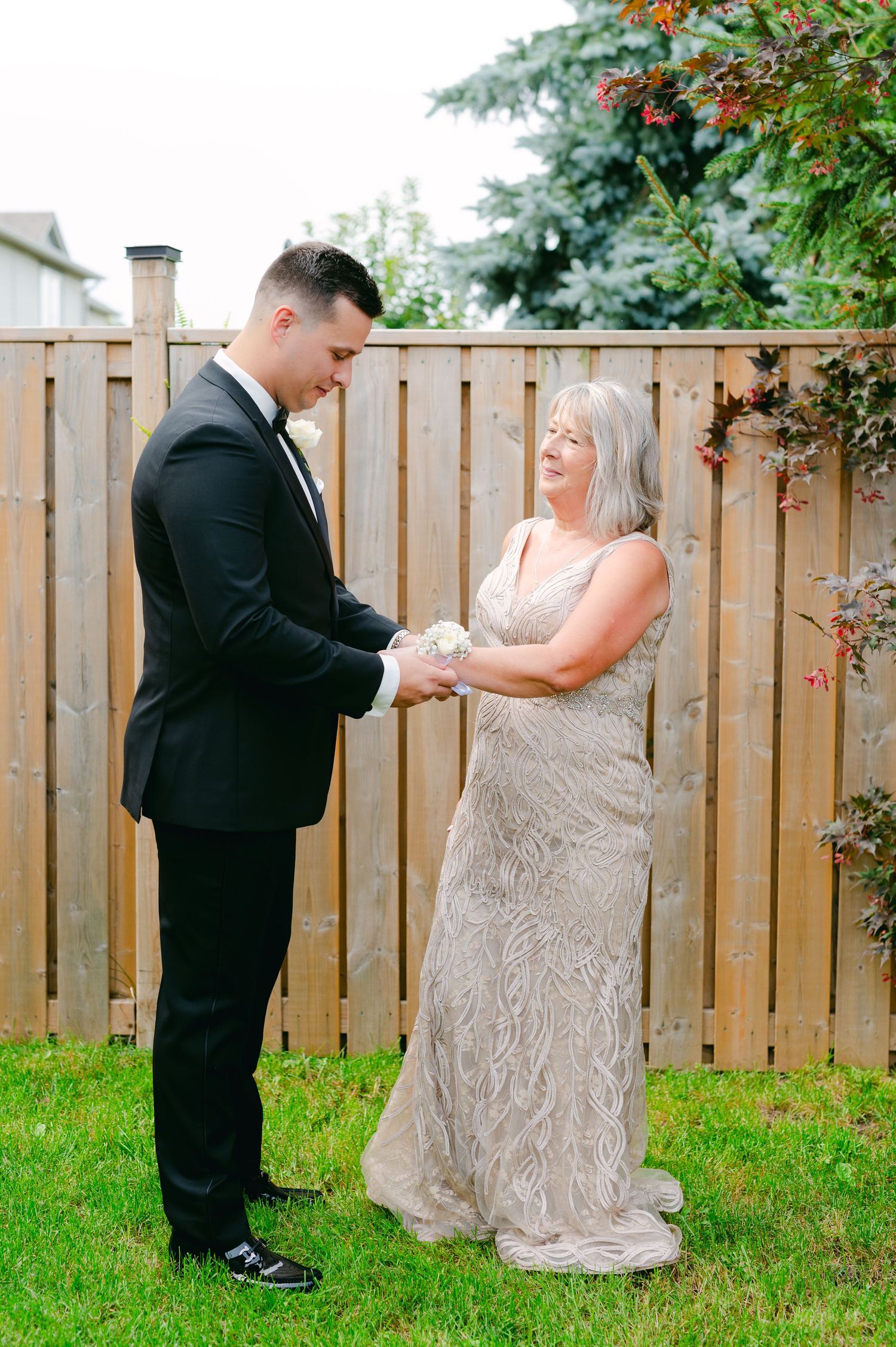 A touching moment in a backyard between two people during a formal occasion.