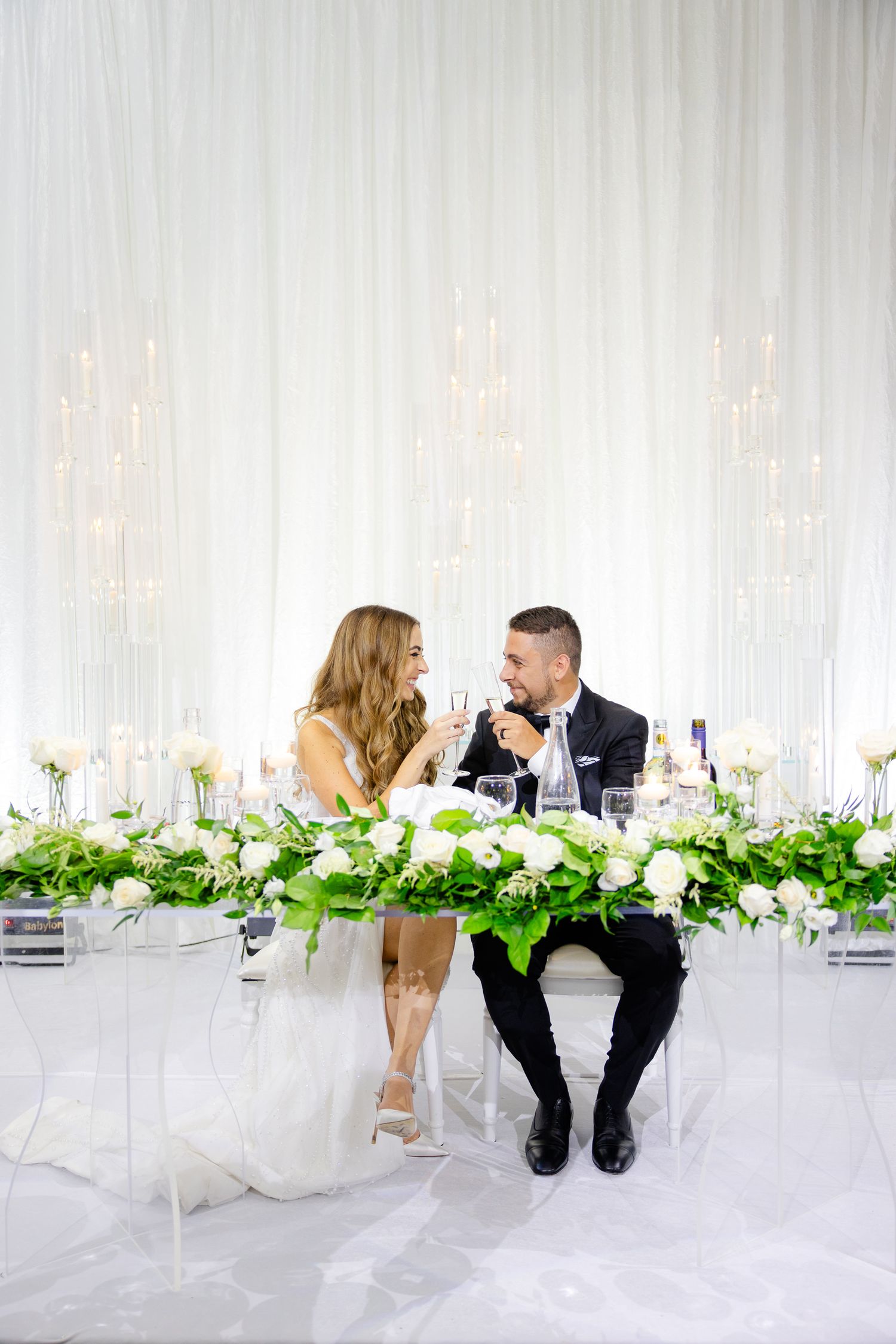 Couple sharing an intimate moment at their white floral decorated sweetheart table.