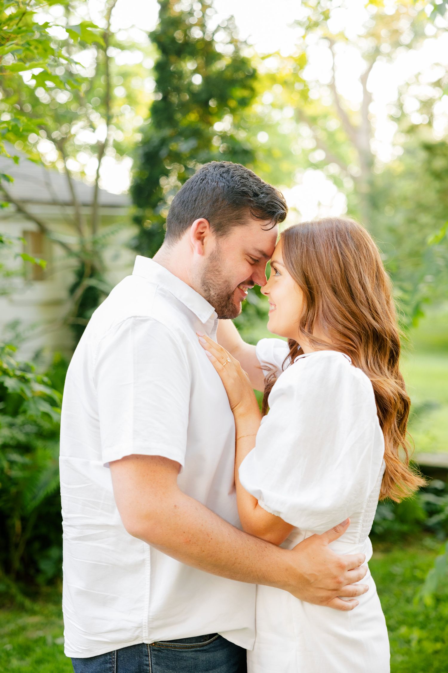 An intimate moment captured between two people in white clothing during an outdoor photoshoot.