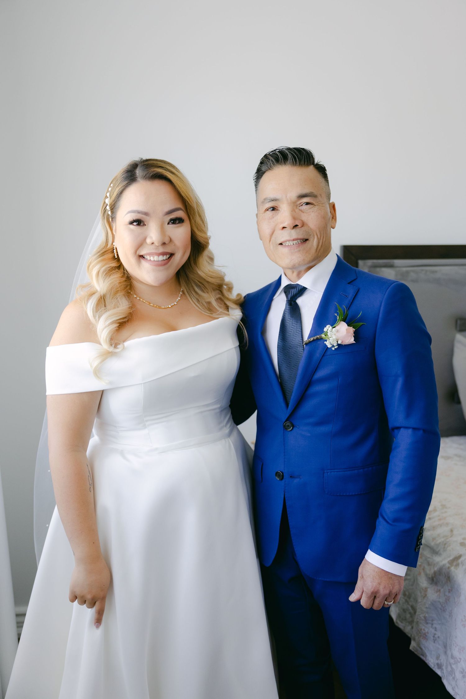 Wedding couple poses together, with bride in white gown and groom in vibrant blue suit.