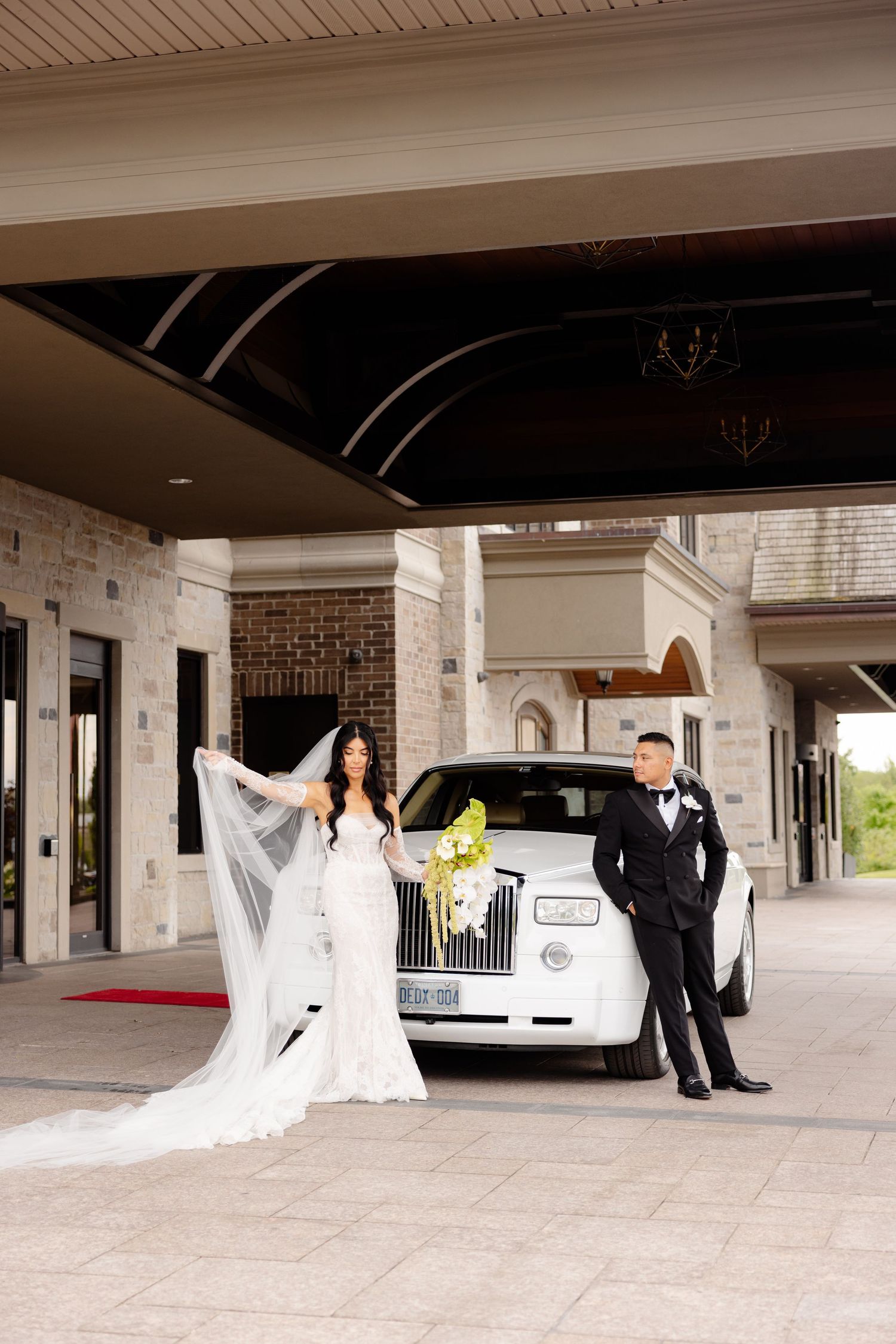 A romantic wedding photoshoot series with a classic white car at a covered entrance of a brick building.