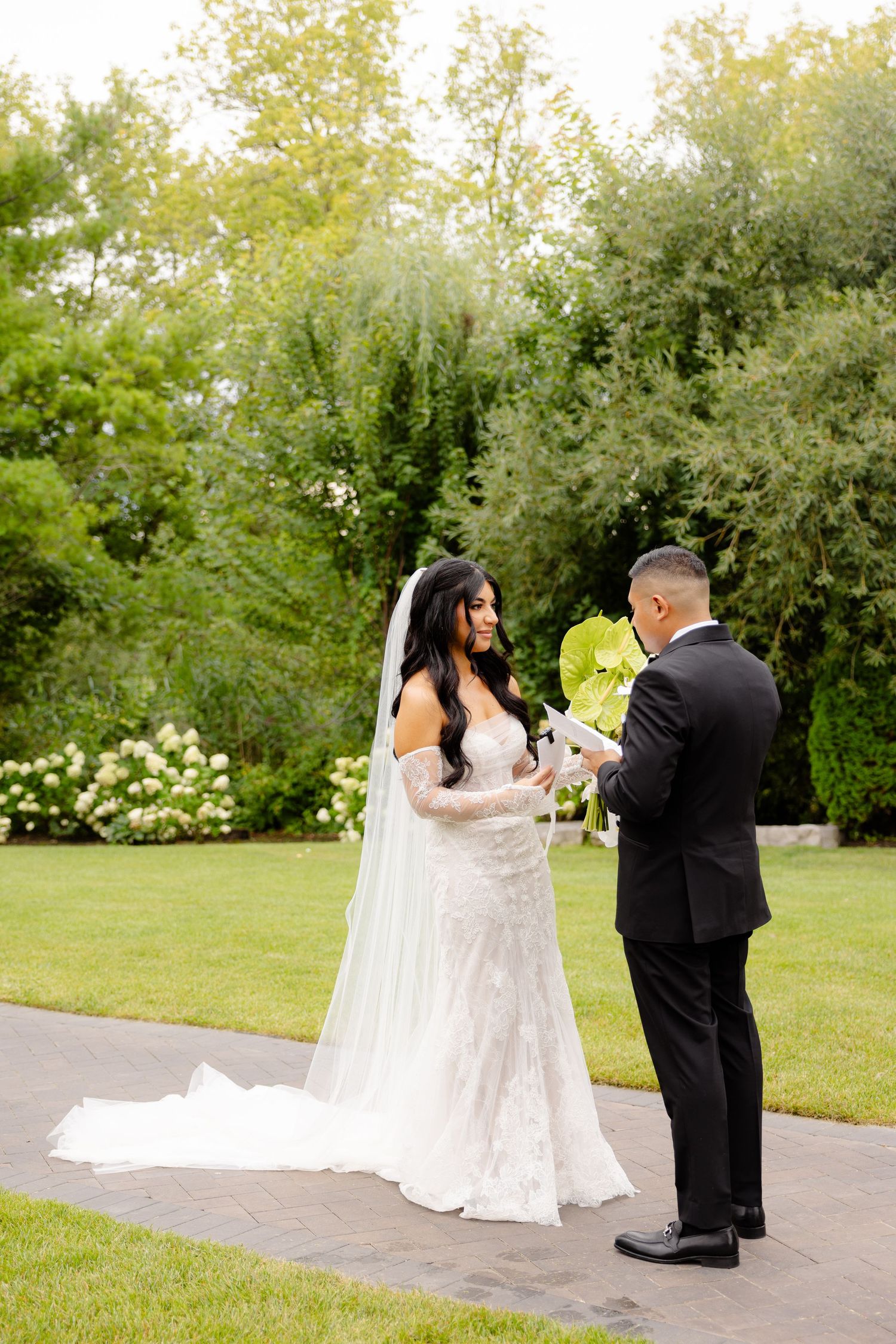 A couple exchanges vows during an intimate outdoor garden wedding ceremony on a lush summer day.