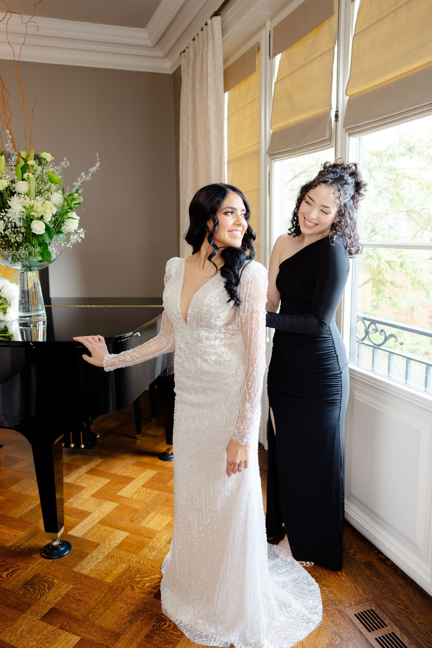 Wedding dress fitting in sunny room with parquet floors and grand piano.