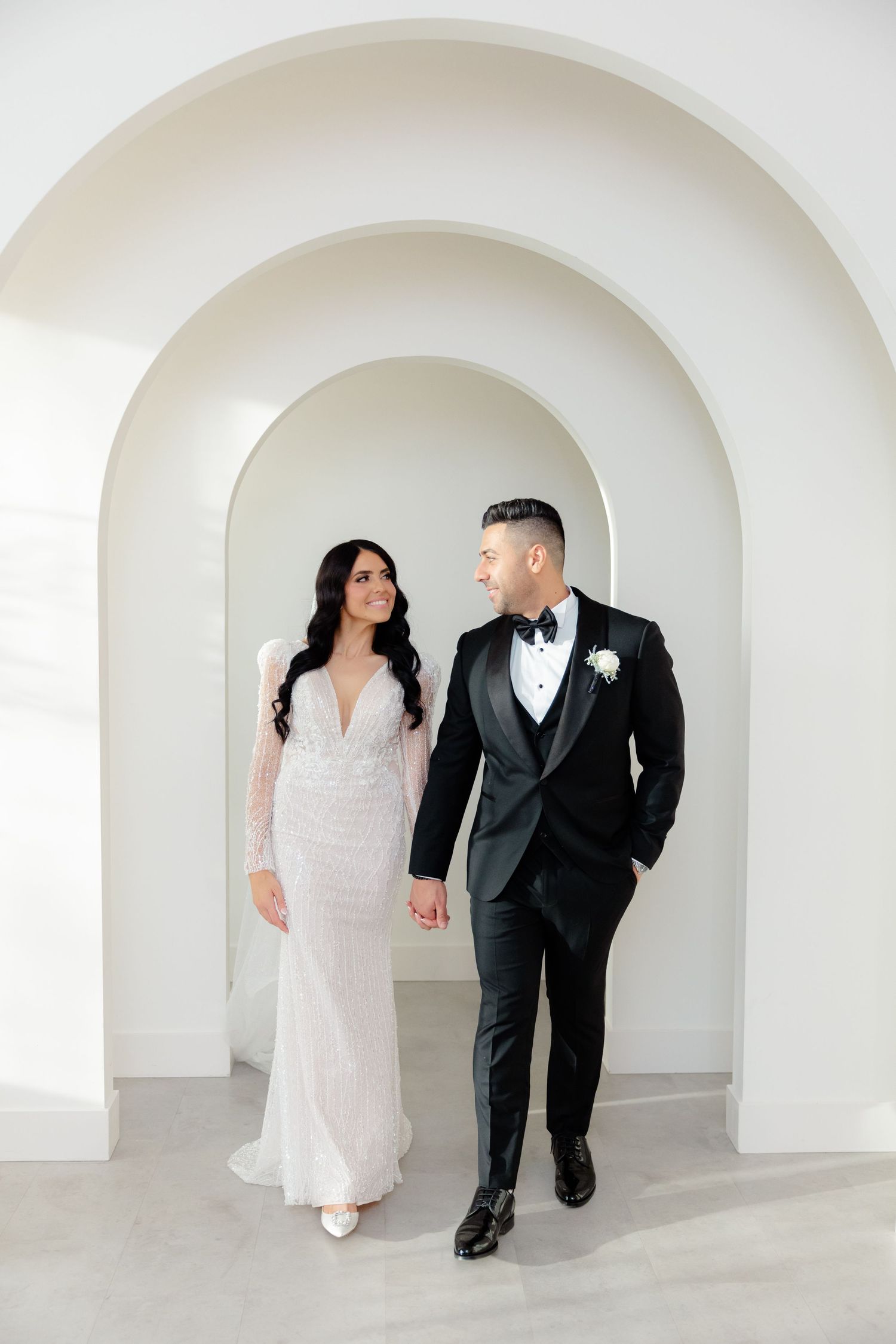 Modern wedding portrait with couple walking through contemporary white archway.