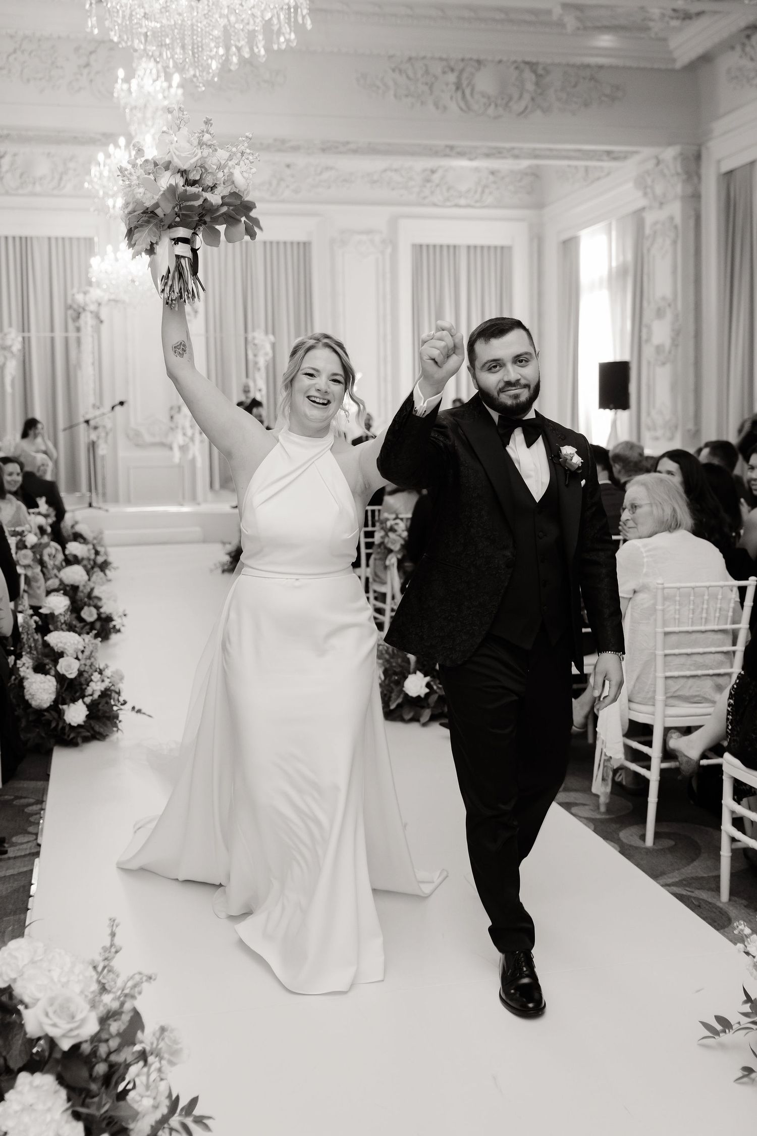 A black and white photo series showing a couple dancing together at an elegant wedding reception in a grand ballroom.