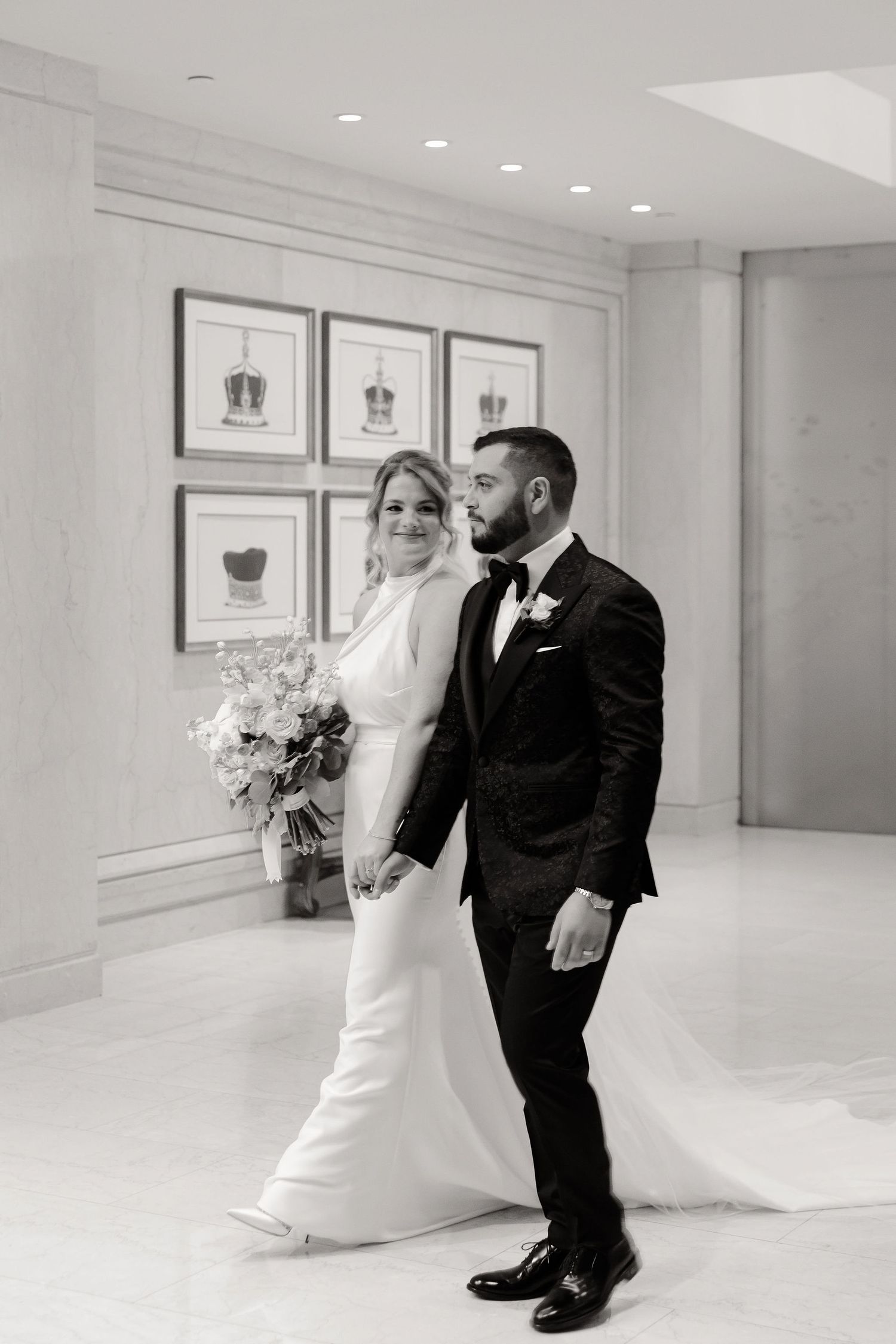 Wedding couple poses in a bright white modern space with framed artwork on the walls.