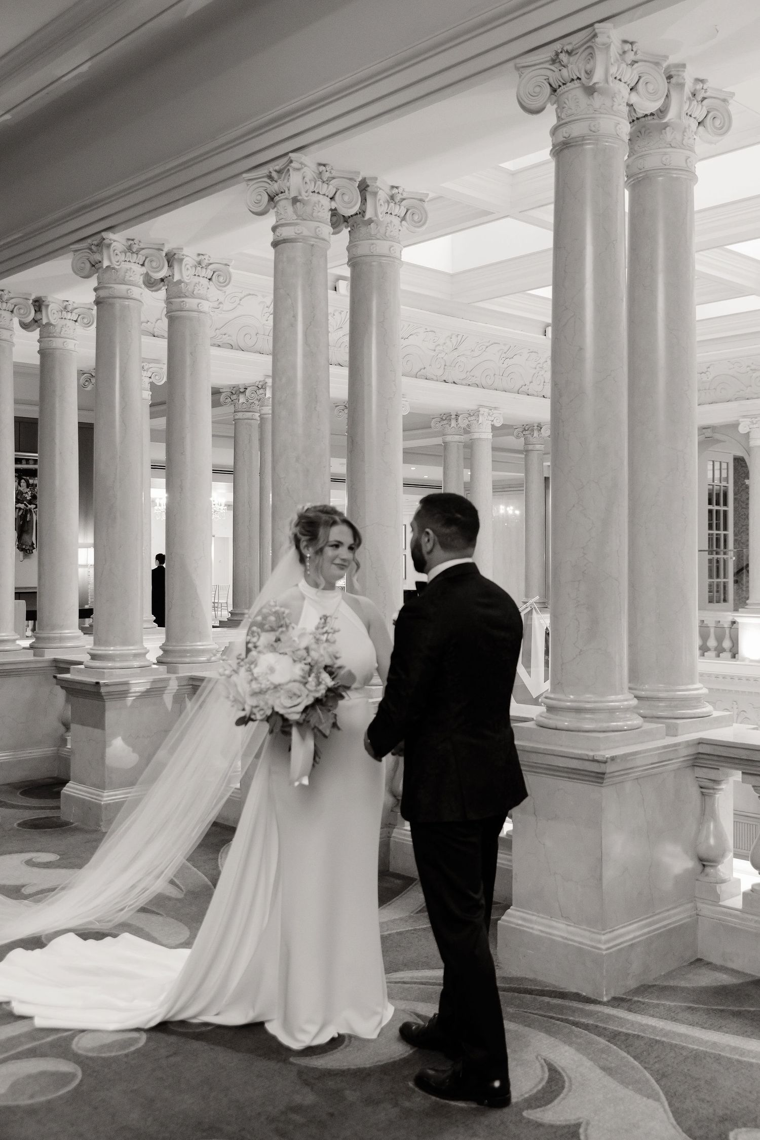 Black and white wedding photos showing couple posing between classical white columns.