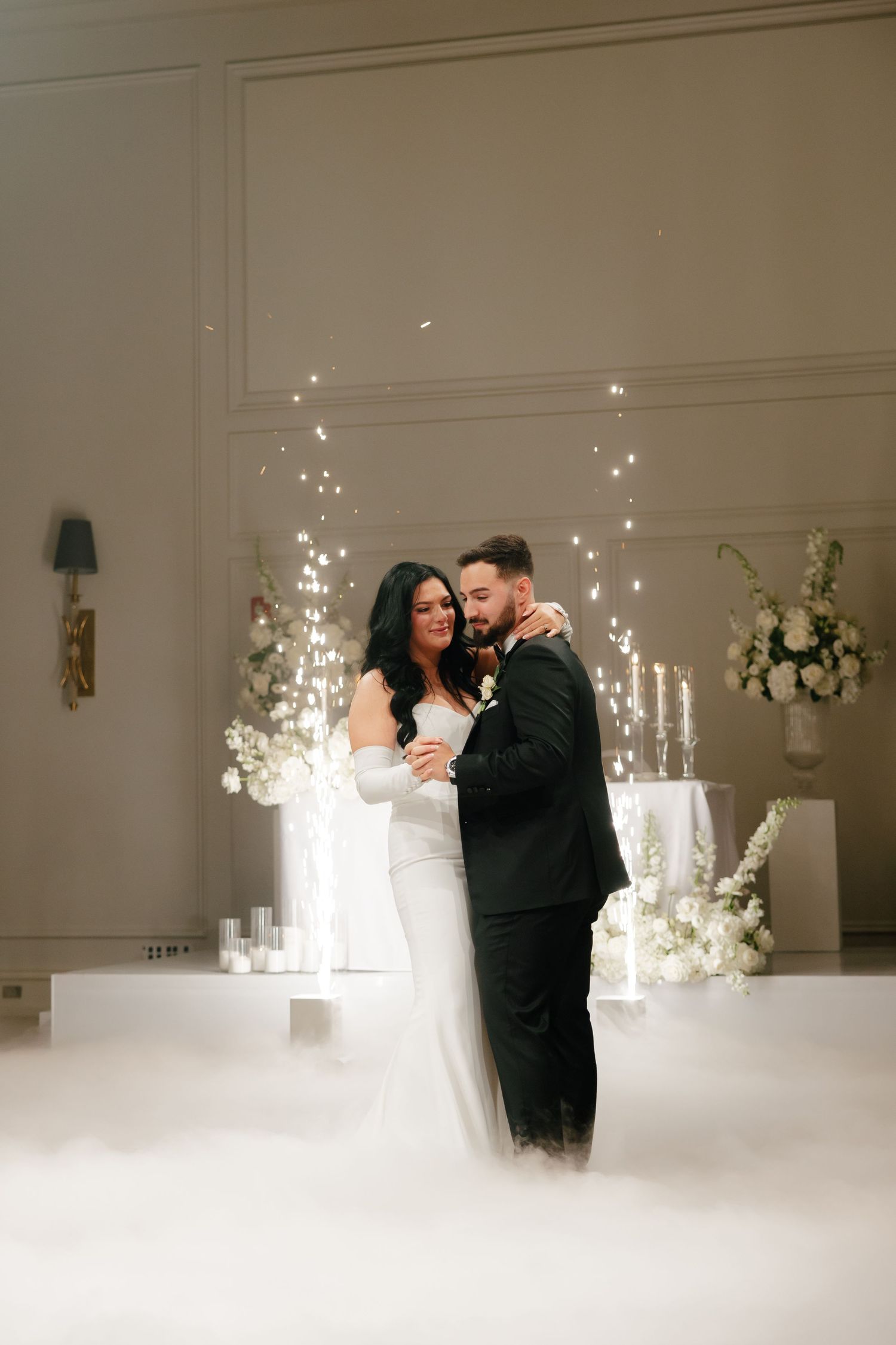 Newlyweds share an intimate moment during their first dance surrounded by fog and twinkling lights.