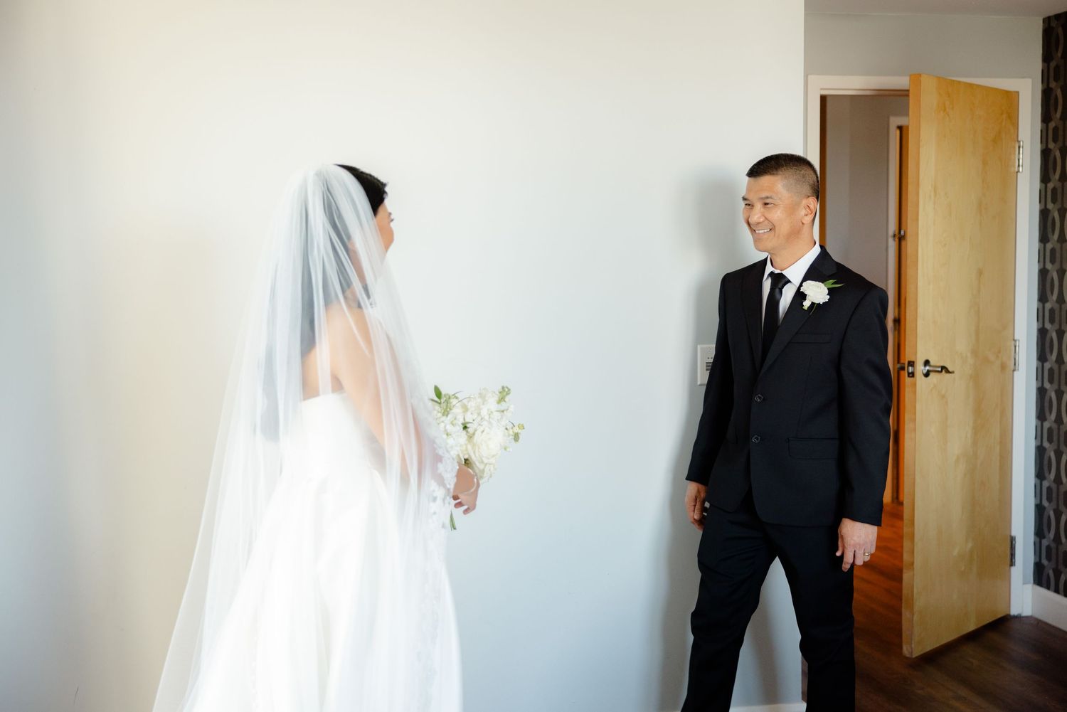 Wedding first look moment with bride in white gown and groom in classic black suit.