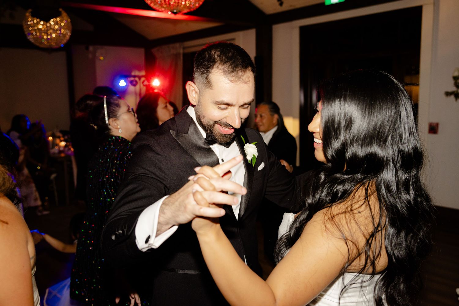 Couple dancing together during wedding reception celebration under party lights.