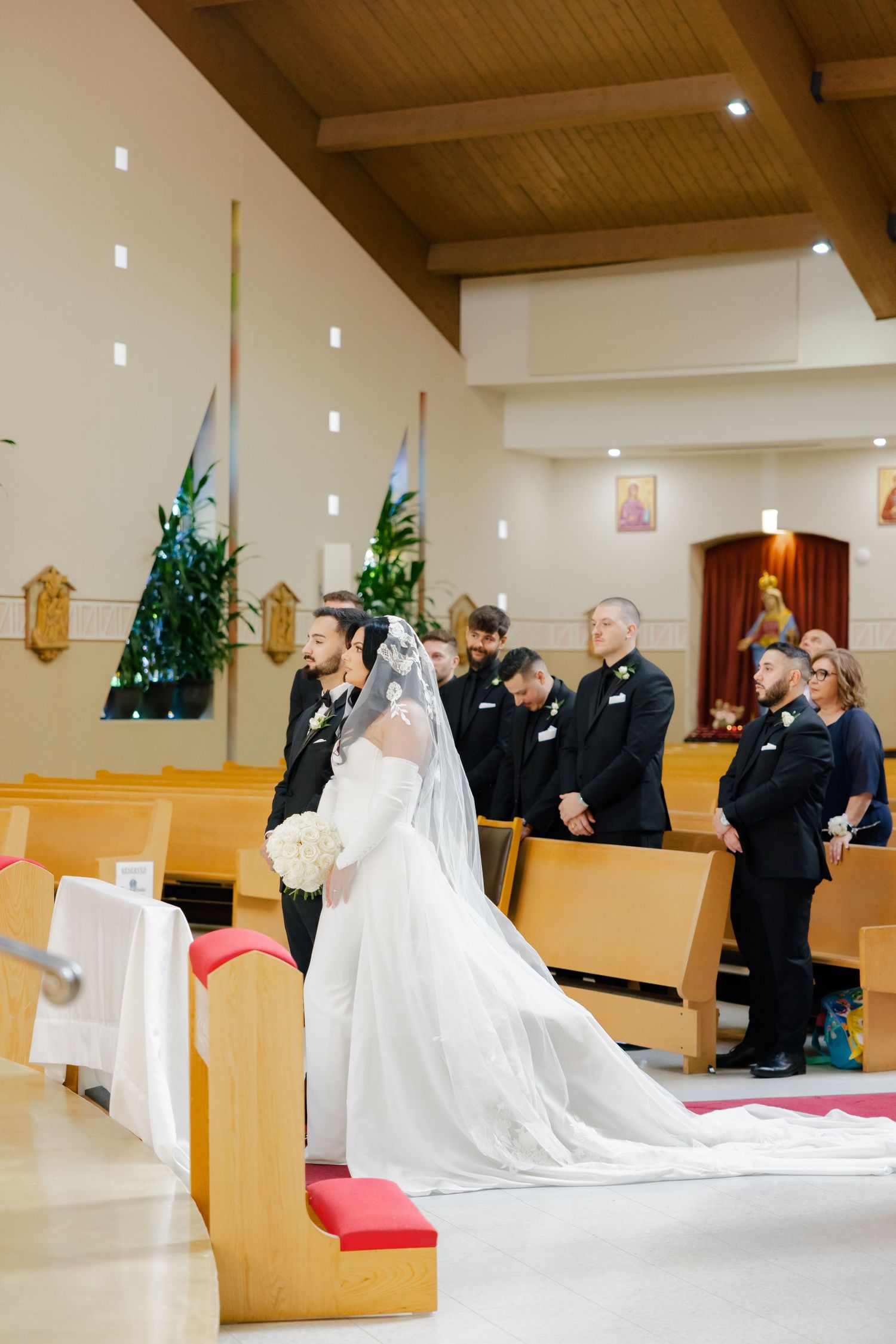Wedding ceremony in progress inside a modern church with wooden ceiling beams.