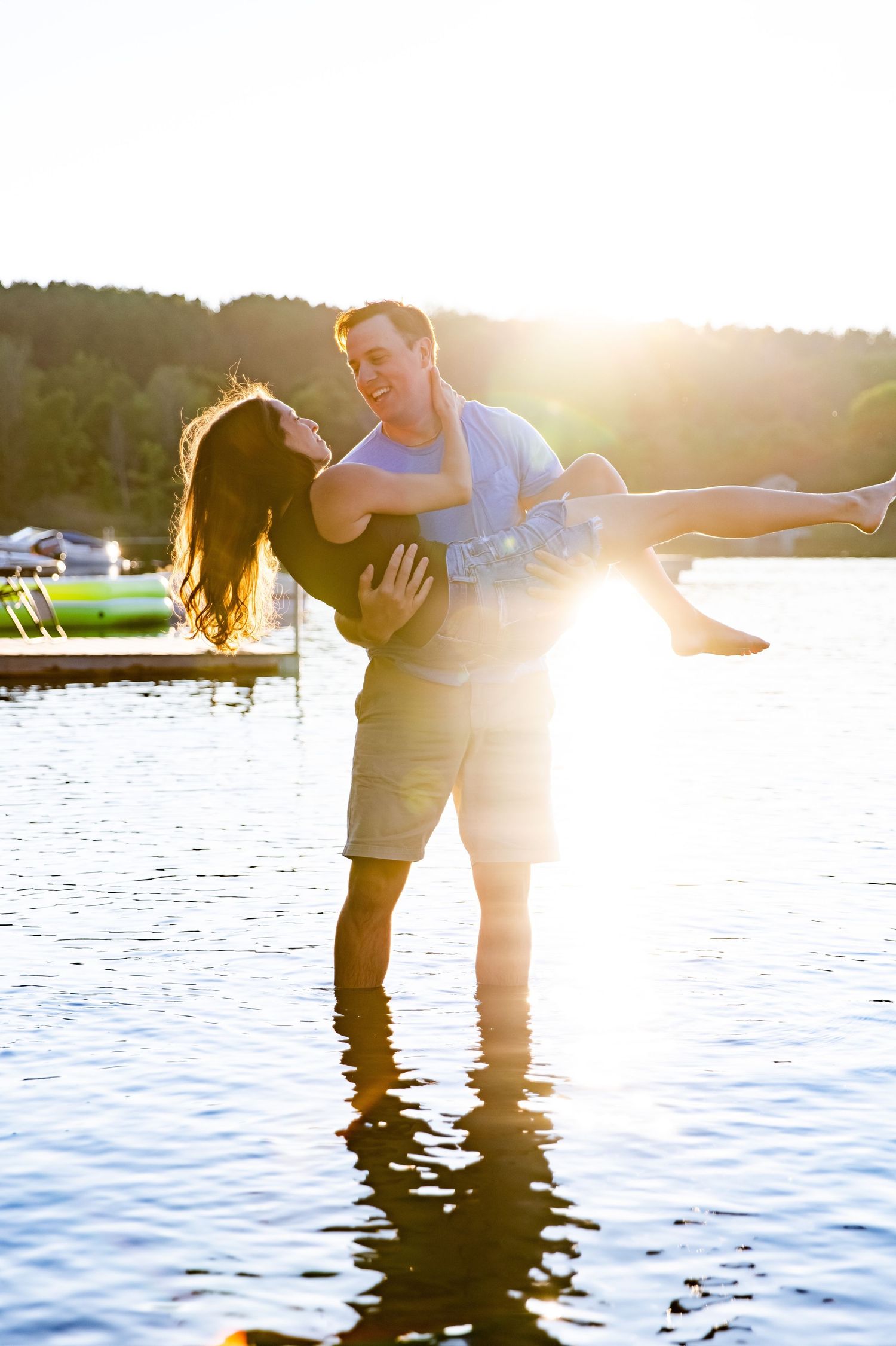 Playful moment captured at sunset as couple poses in lake water.