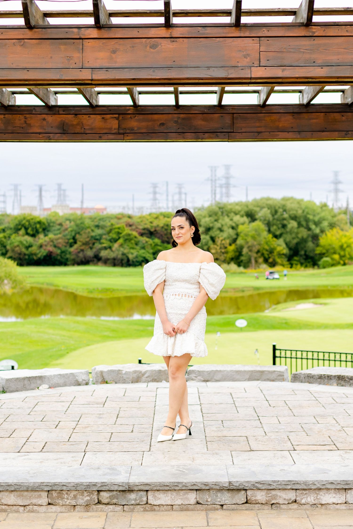 Rustic wooden pergola overlooking a scenic golf course with power lines in the distance.