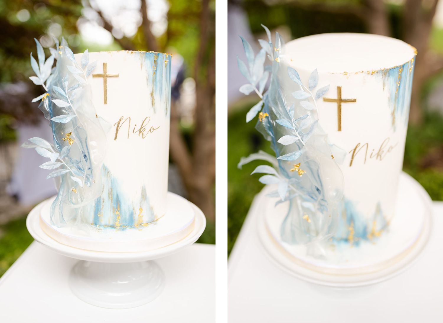 White baptism cake decorated with light blue watercolor design, gold cross and delicate floral accents.