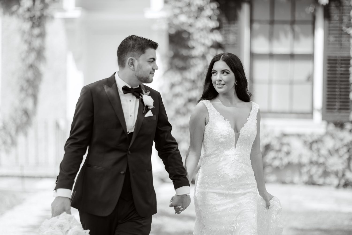 An elegant black and white wedding photo of a couple walking together and sharing a sweet moment.