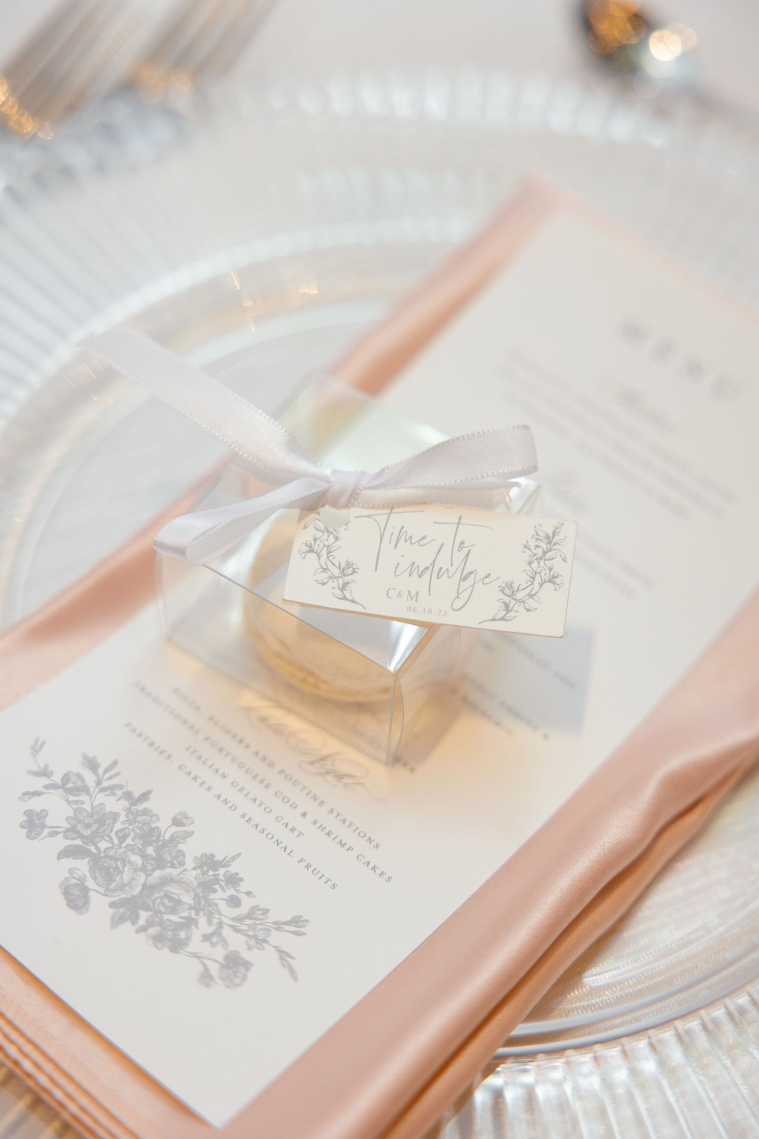 Delicate wedding favor box with ribbon and floral menu card in soft peach tones.